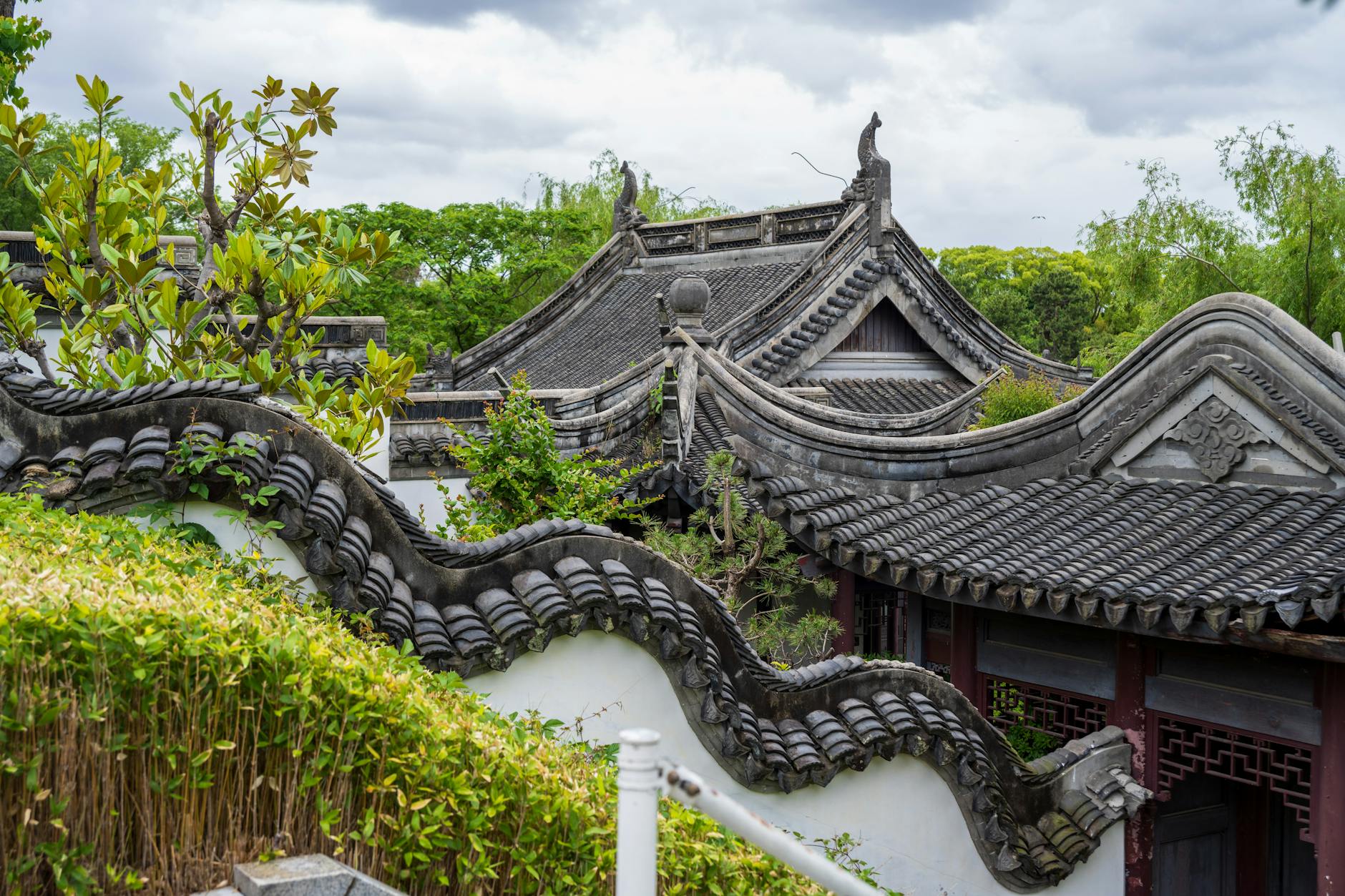 Captivating view of traditional Chinese garden architecture featuring intricate curved roofs amidst lush greenery.