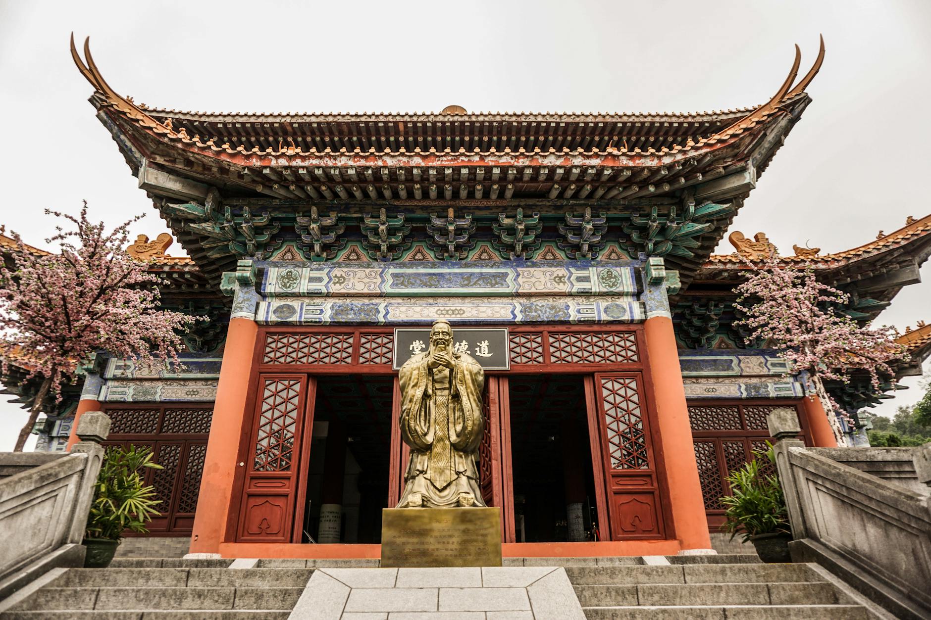 A detailed view of a golden statue in front of an ornate temple entrance in Guangzhou, China, showcasing traditional architecture.