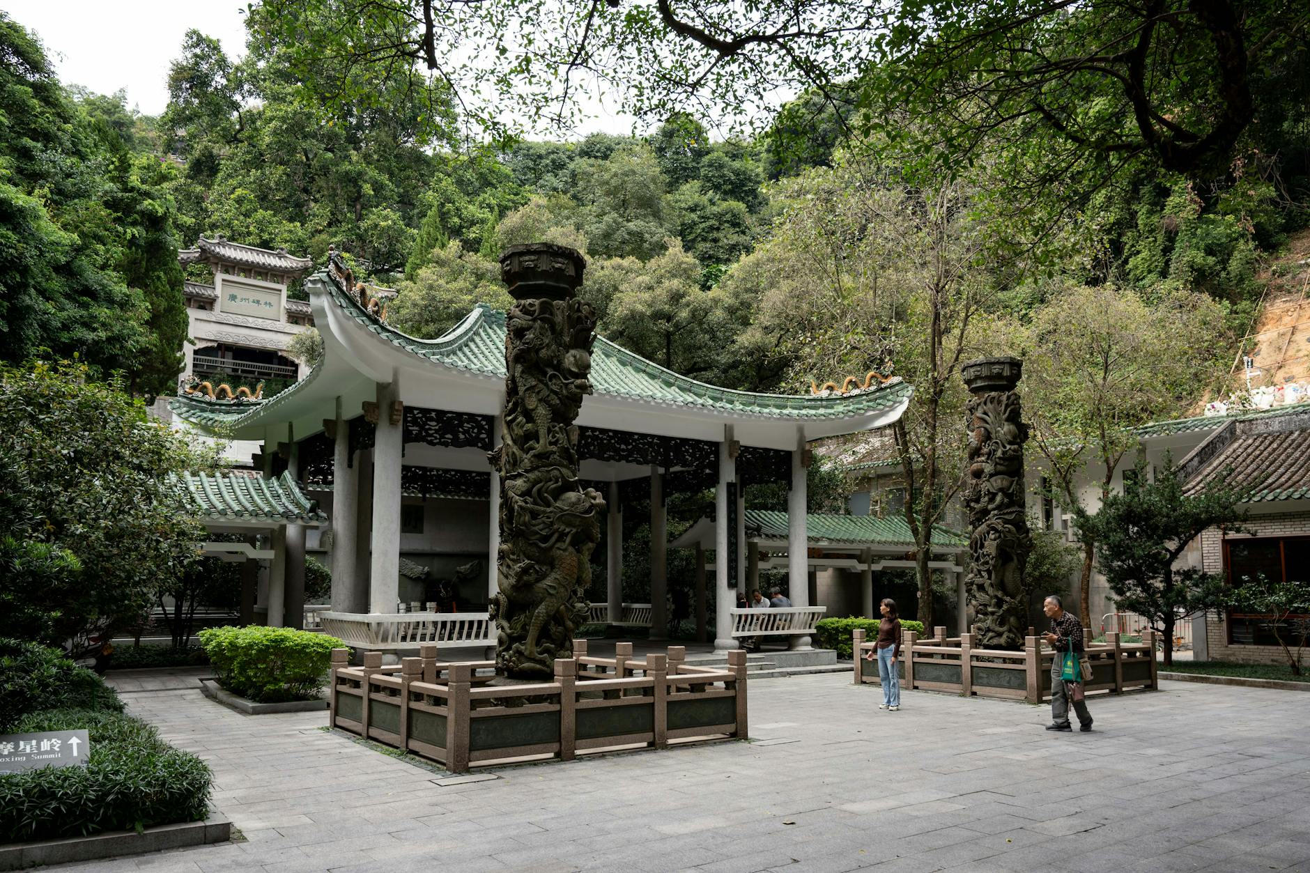 Beautiful traditional pavilion and intricately carved columns in a lush Guangzhou park setting.