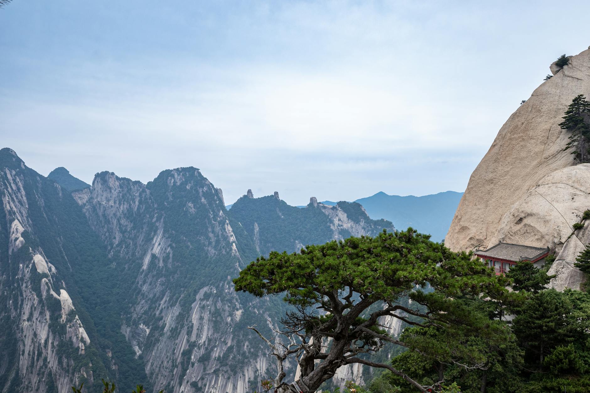 Stunning landscape of Mount Hua's rugged peaks and ancient temple nestled on a rocky cliff.