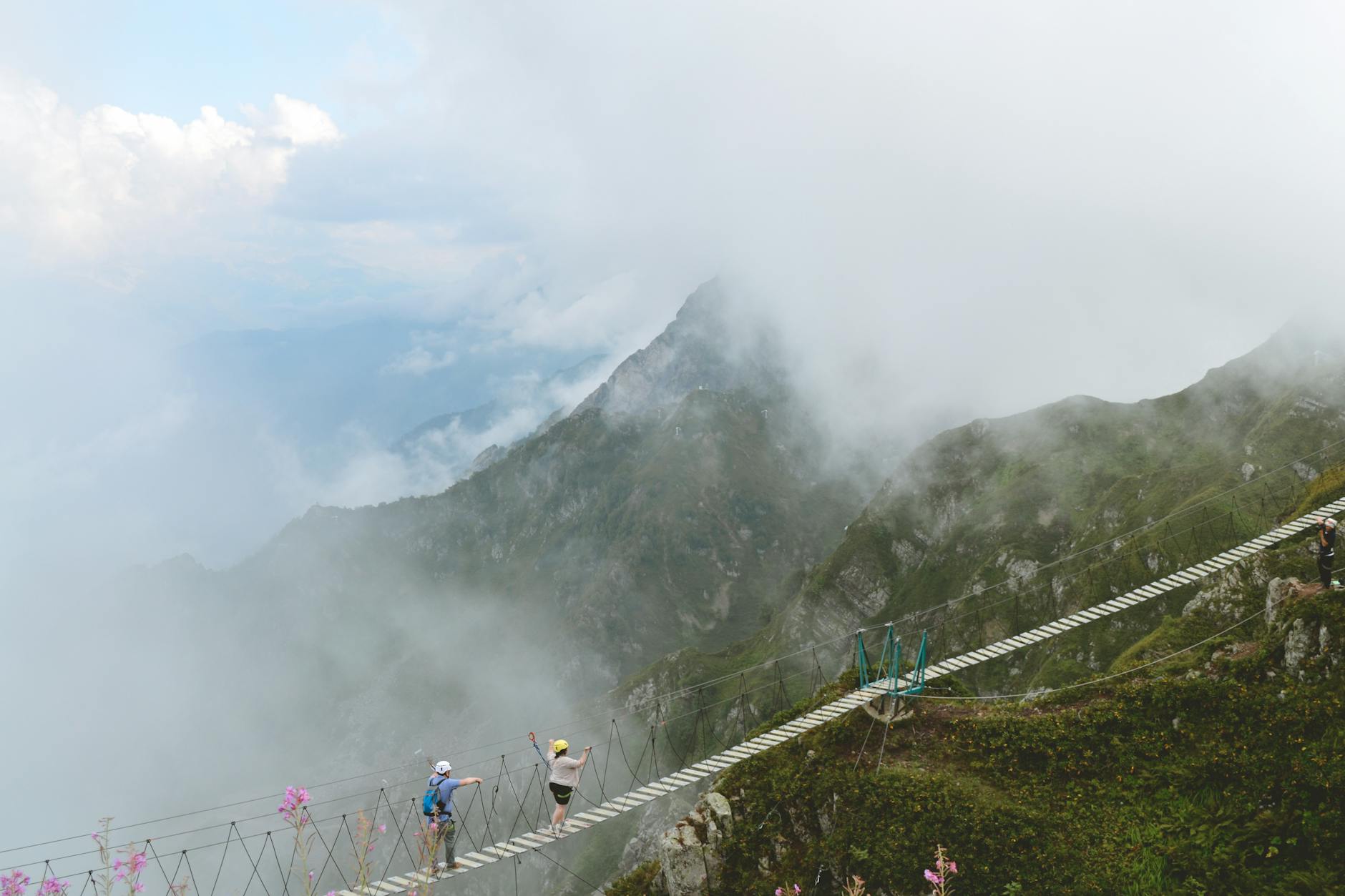 Two people walk a foggy mountain suspension bridge in Krasnodar, Russia.