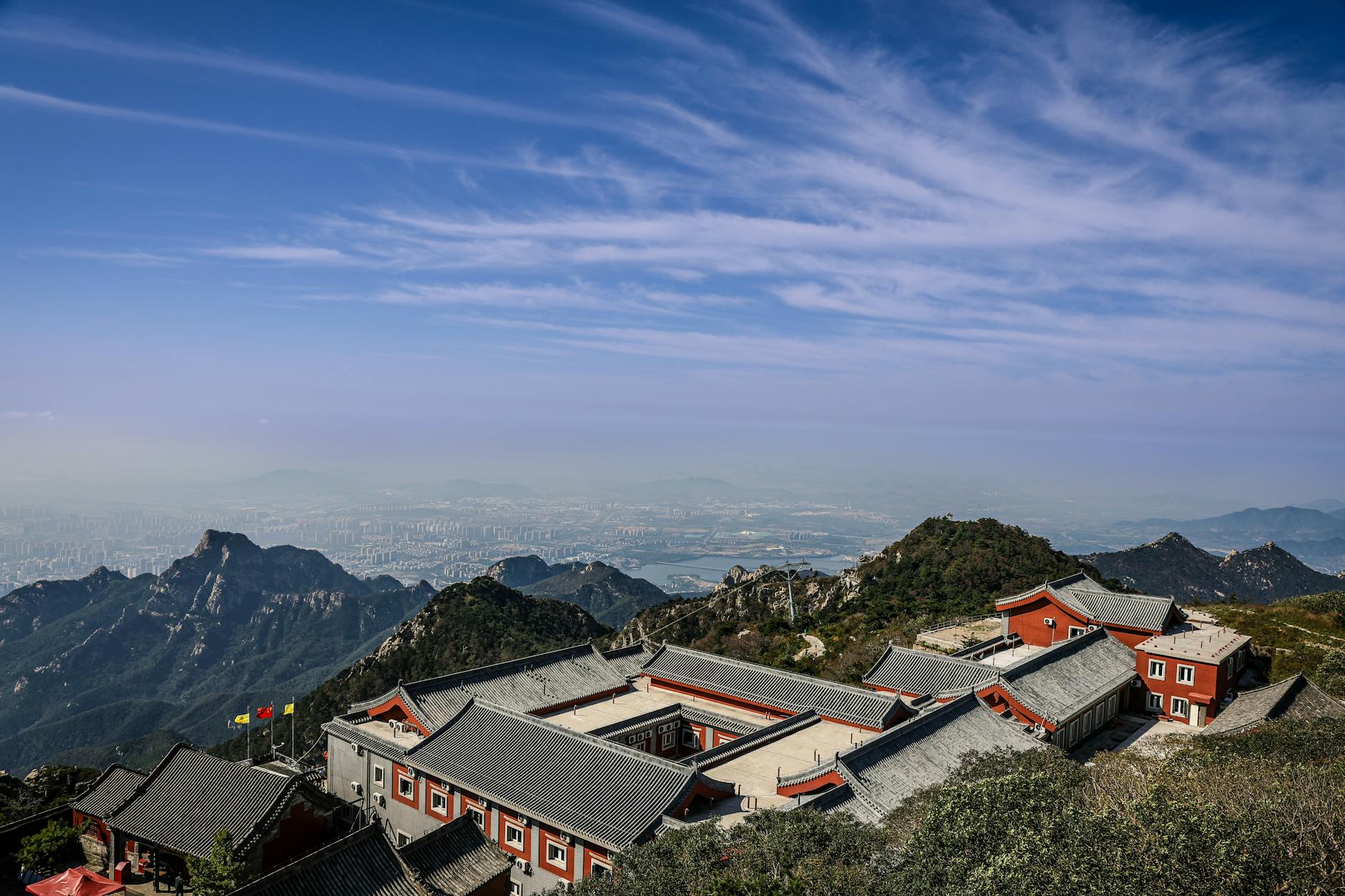 Scenic aerial view of ancient temple rooftops nestled in mountain landscape under clear blue sky.