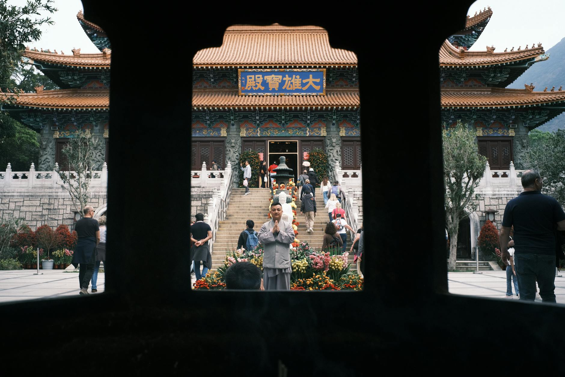 Monk praying in front of a traditional Buddhist temple with cultural architectural features.