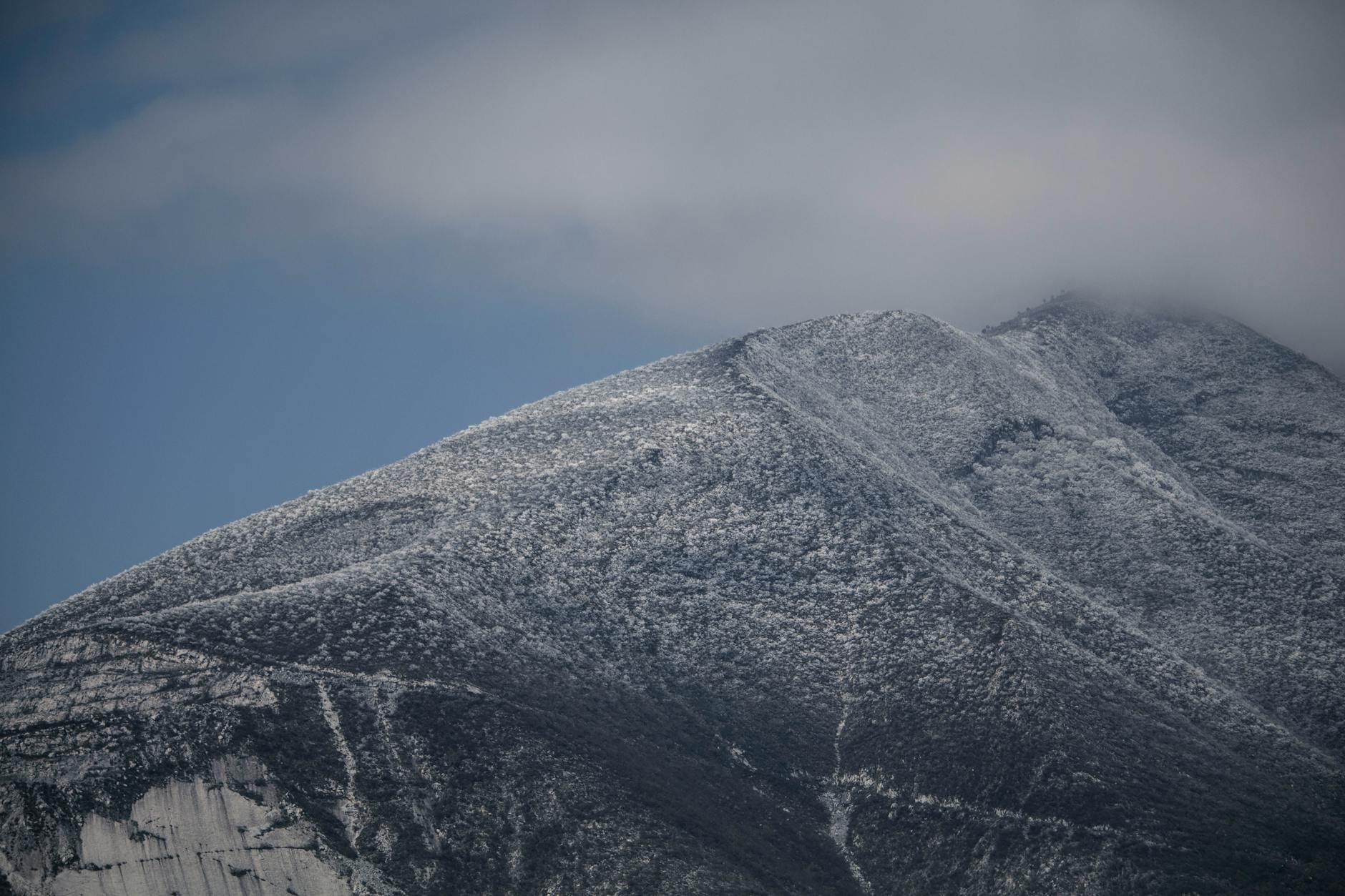 Breathtaking view of snow-capped Cerro de la Silla in Monterrey, capturing the majestic peak and cloud cover.