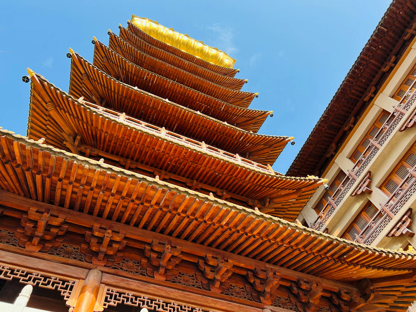 Low-angle view of a traditional Chinese pagoda under a clear blue sky, highlighting intricate woodwork.