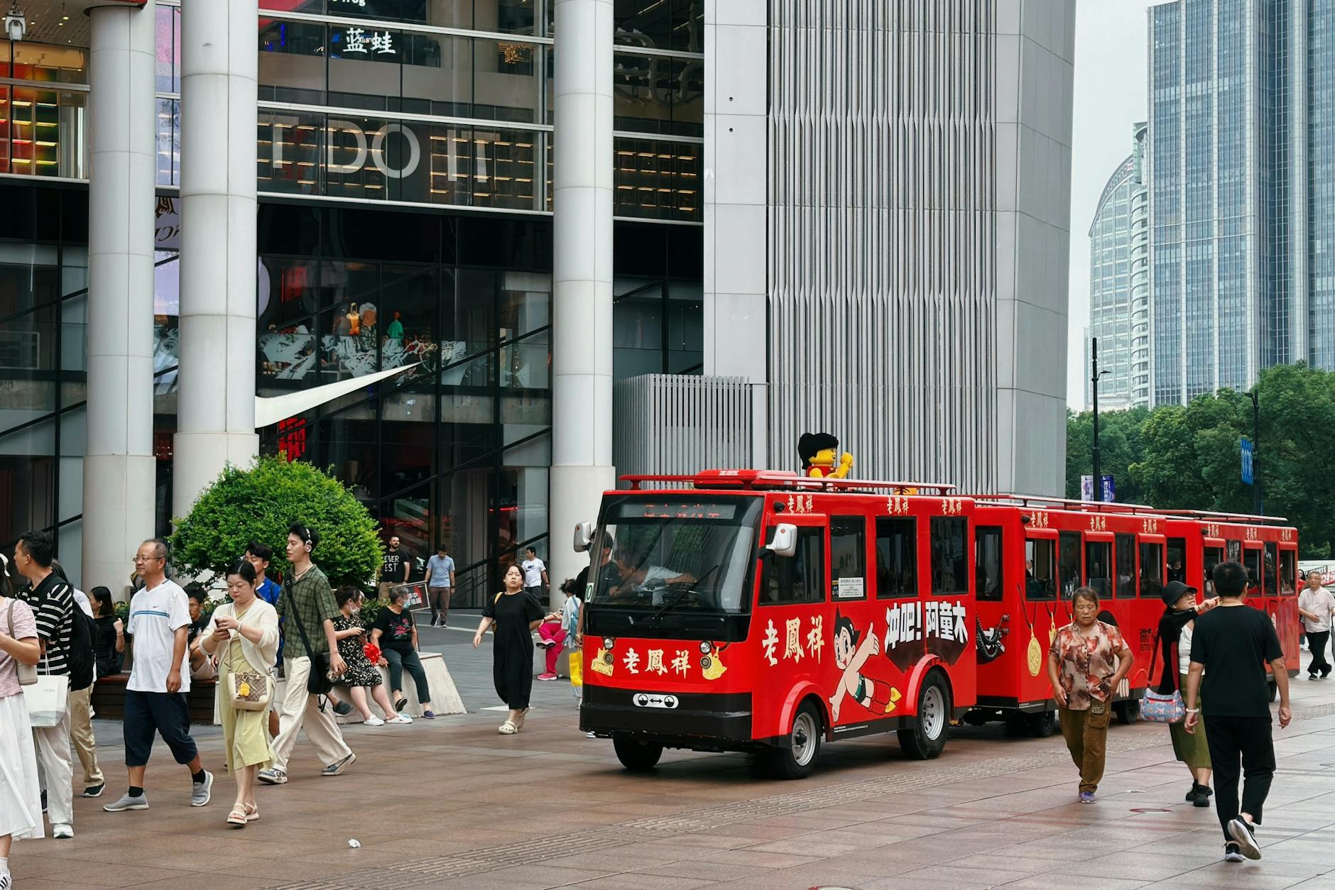 Vibrant street scene with a red tourist bus and pedestrians in Shanghai, China.