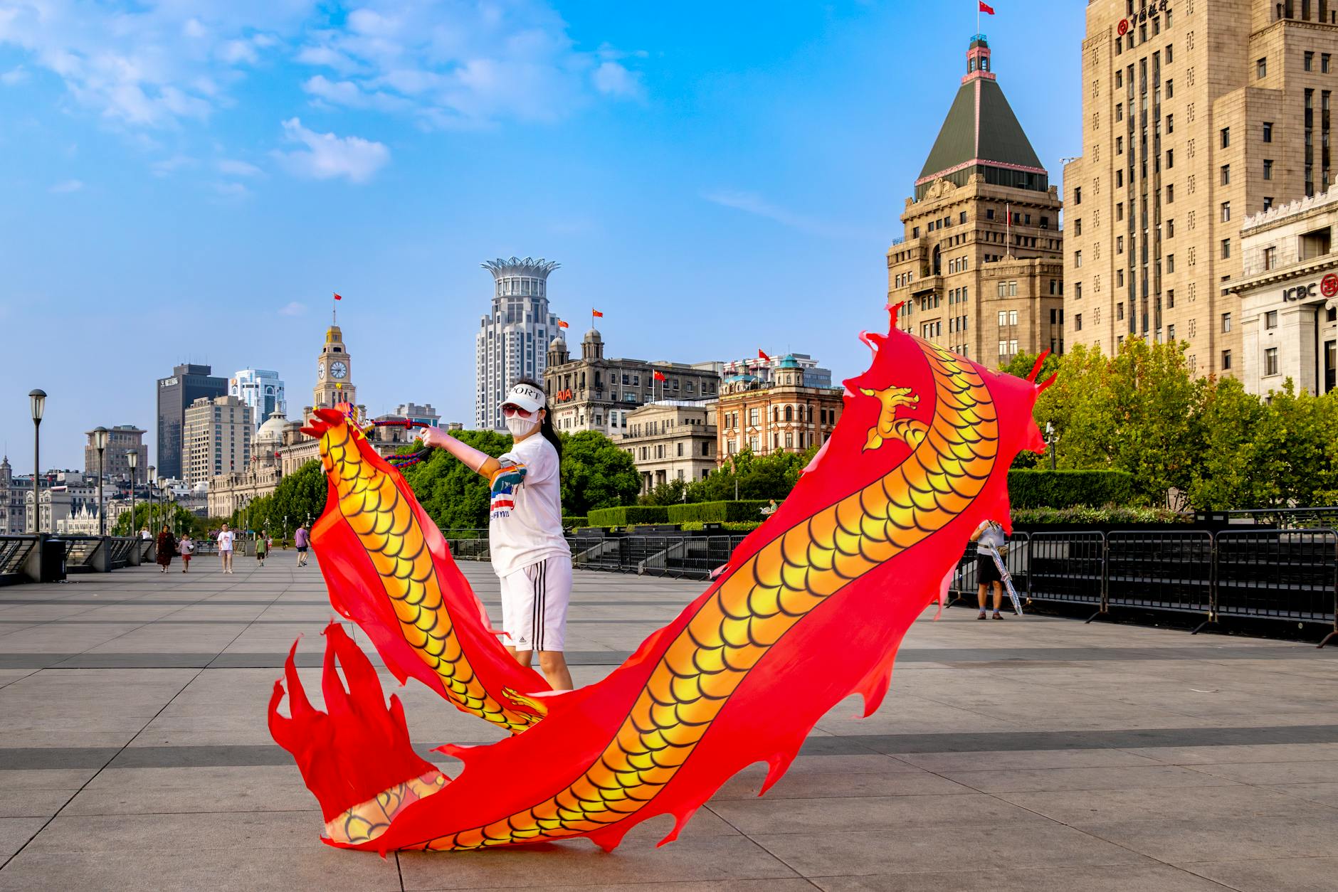 Colorful dragon dance performer on the Bund in Shanghai, China amidst iconic architecture.