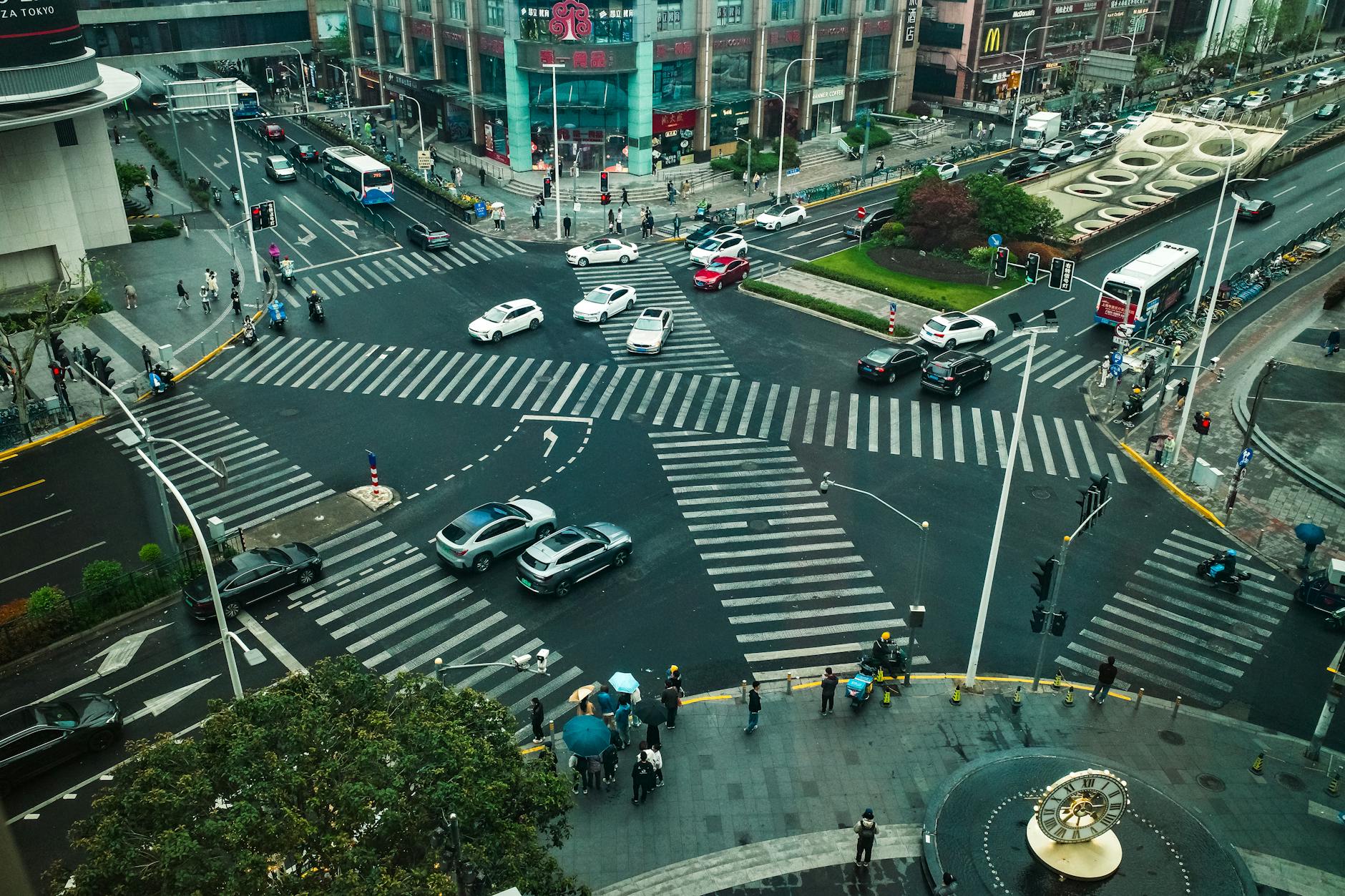 Dynamic aerial view of a bustling intersection in Shanghai, China, with cars and pedestrians.