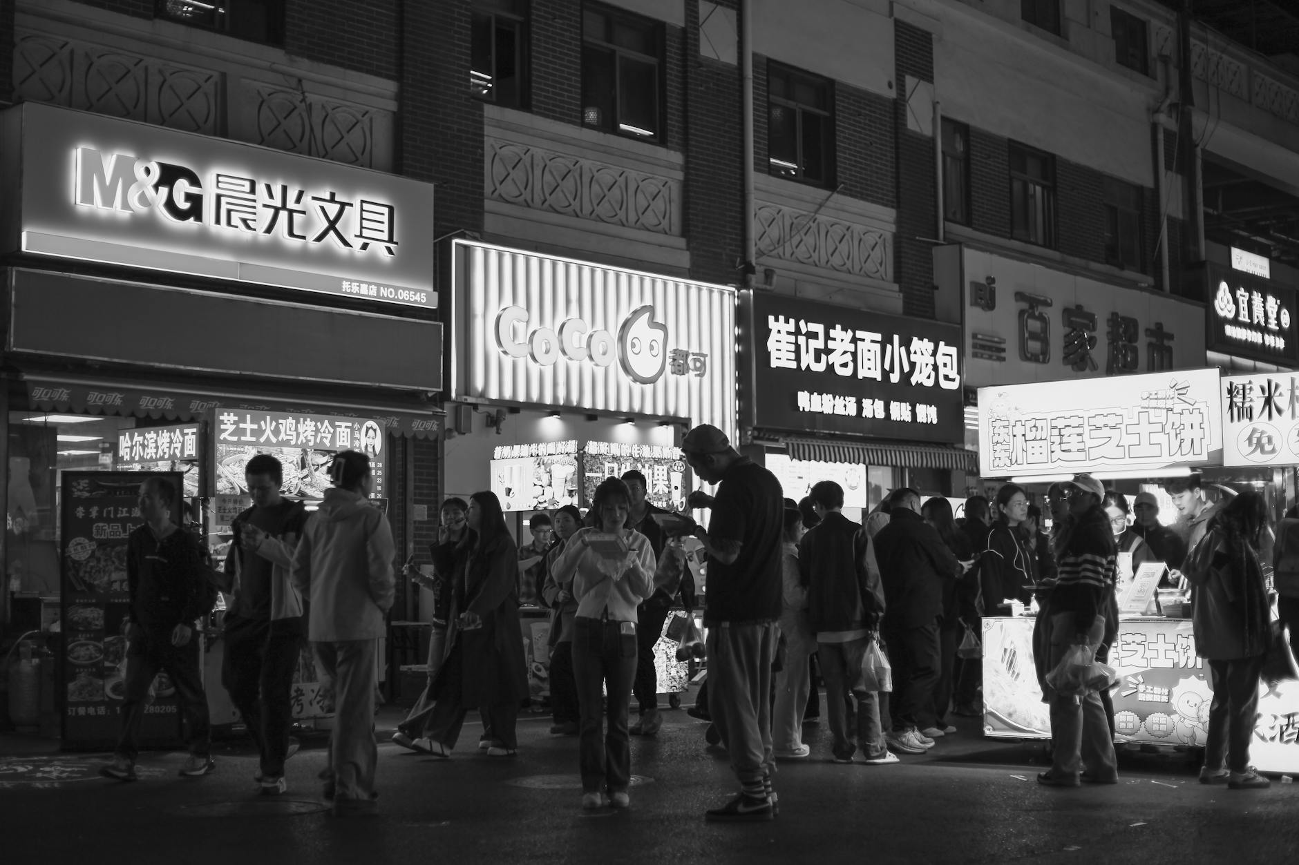 Black and white photo capturing the bustling night scene at a Nanjing street market.