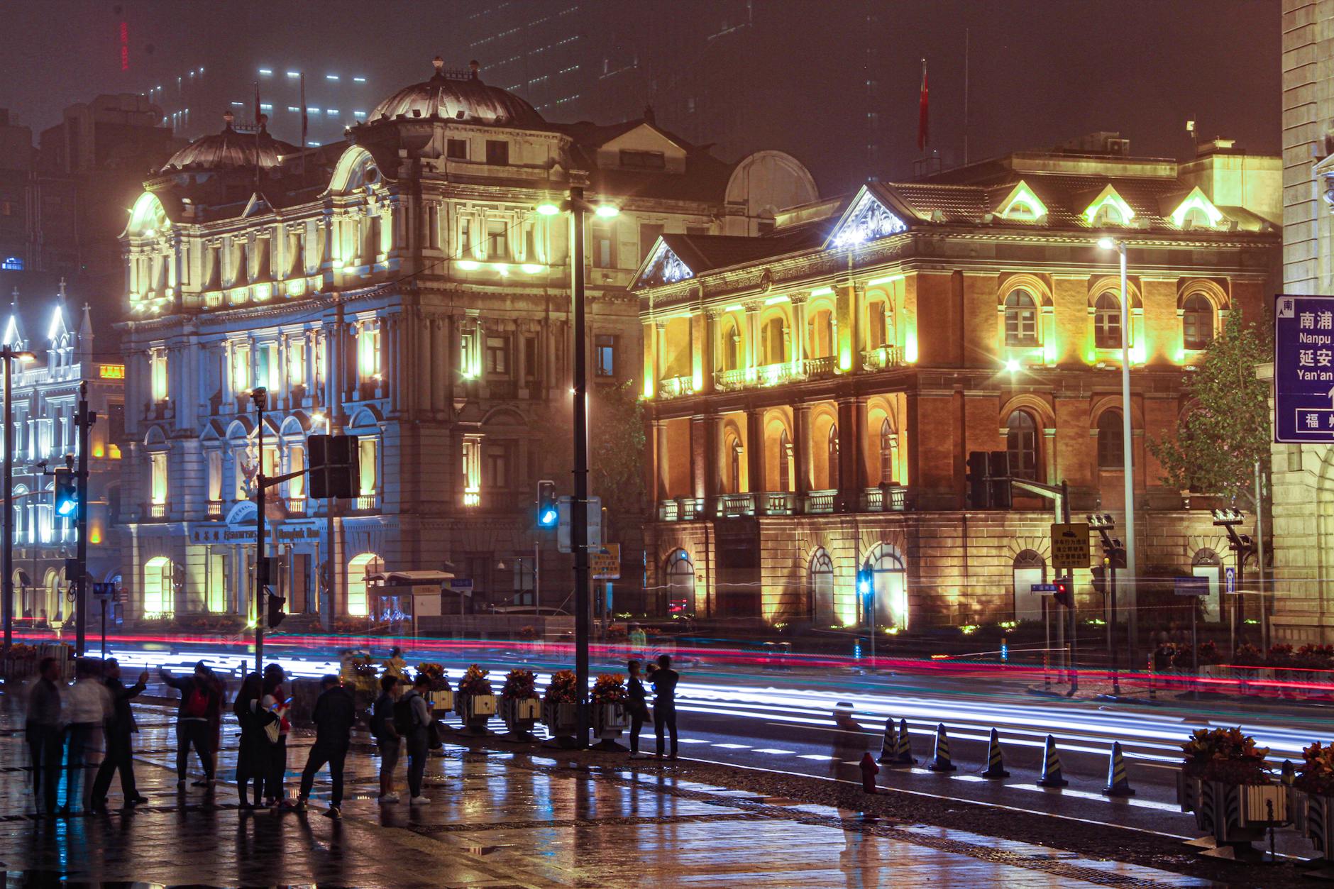 Vibrant night scene of illuminated historical buildings and bustling street in Shanghai, China.