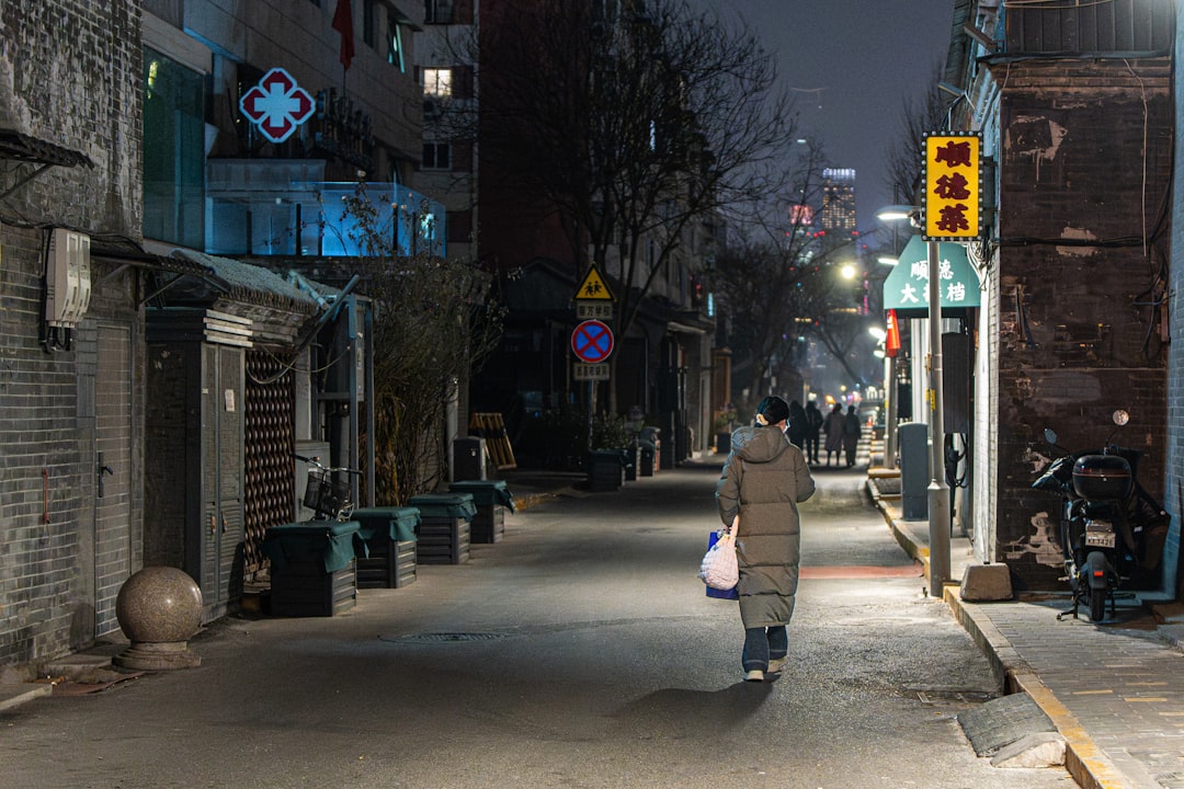 A person walks down a dimly lit street at night.