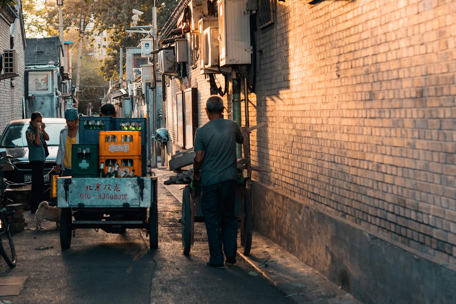 A bustling narrow alley in Beijing's historic hutong, capturing street life at dusk.