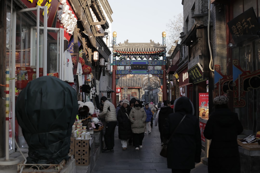 People walk down a narrow street lined with shops.