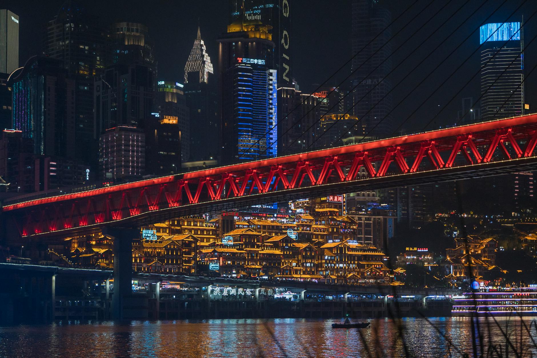 Vibrant night view of Chongqing cityscape featuring a brightly lit bridge and skyline reflections.