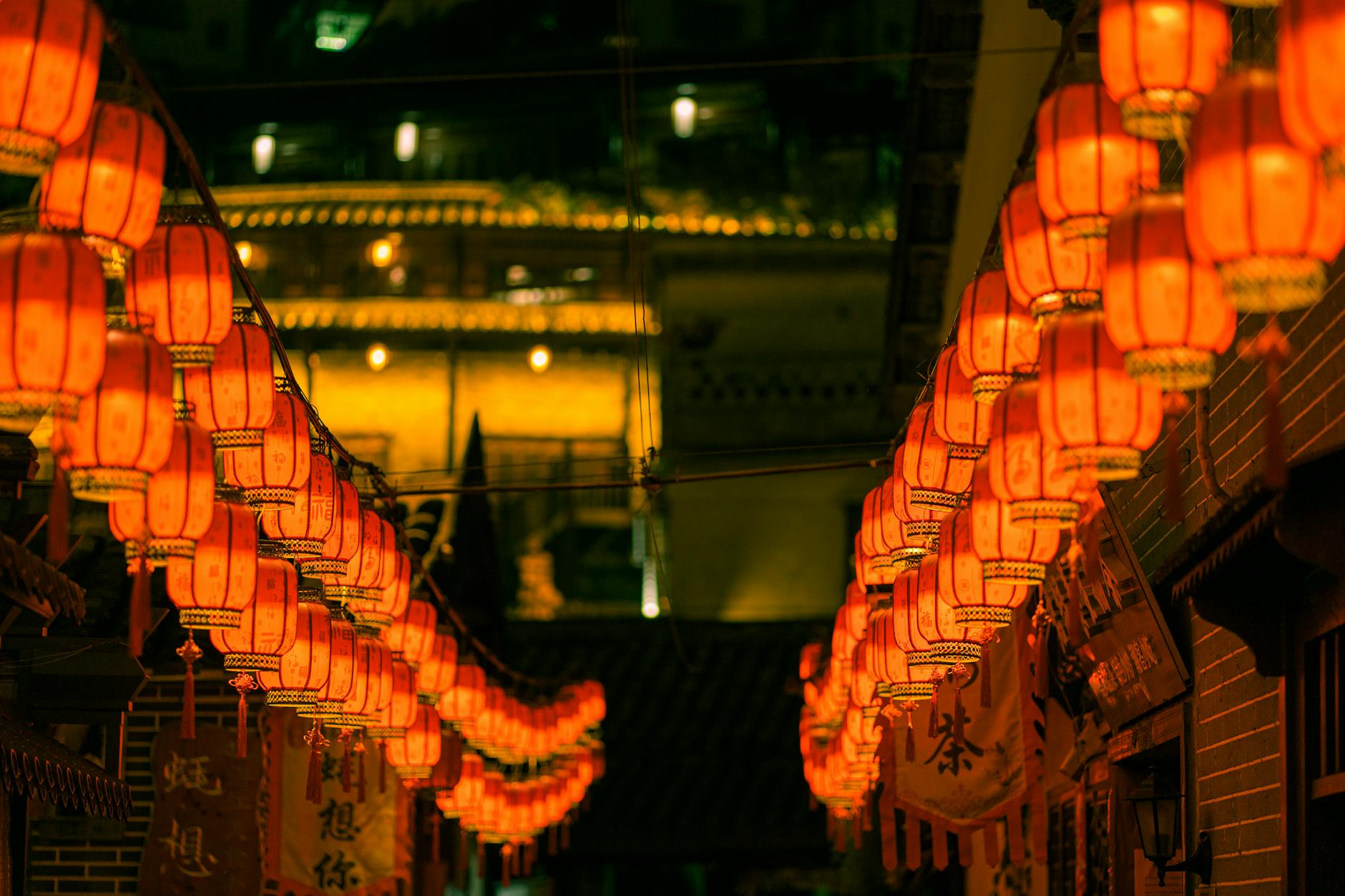 Illuminated red Chinese lanterns line a vibrant street in Shenzhen, China at night.