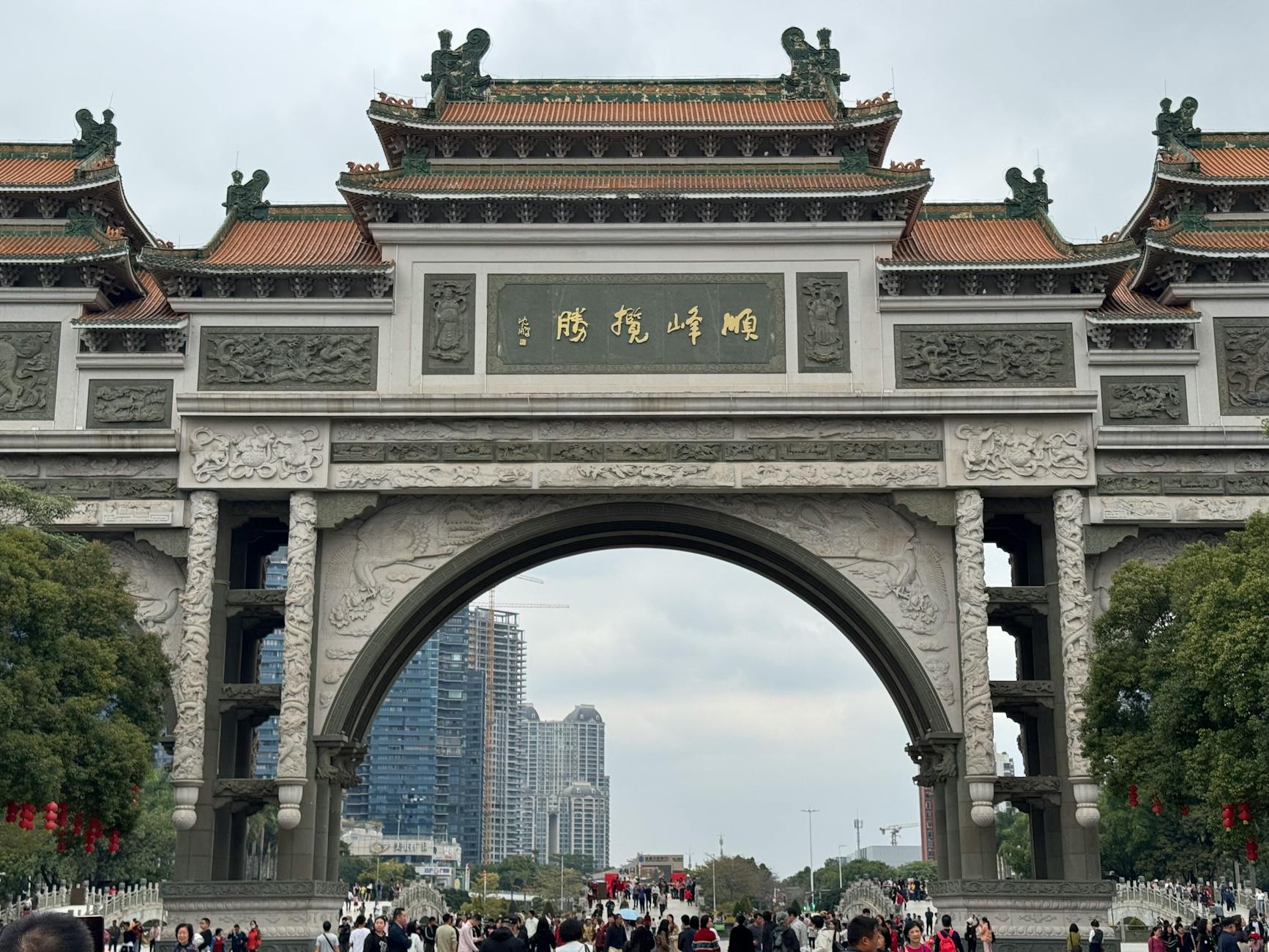 Stunning stone archway with Chinese script and bustling urban backdrop in Shenzhen, China.