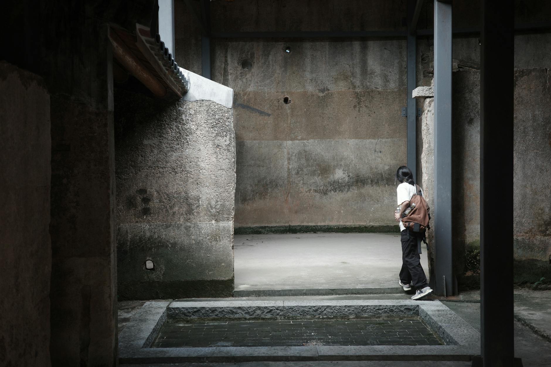 A woman with a backpack explores an old, urban area in Shenzhen, China.