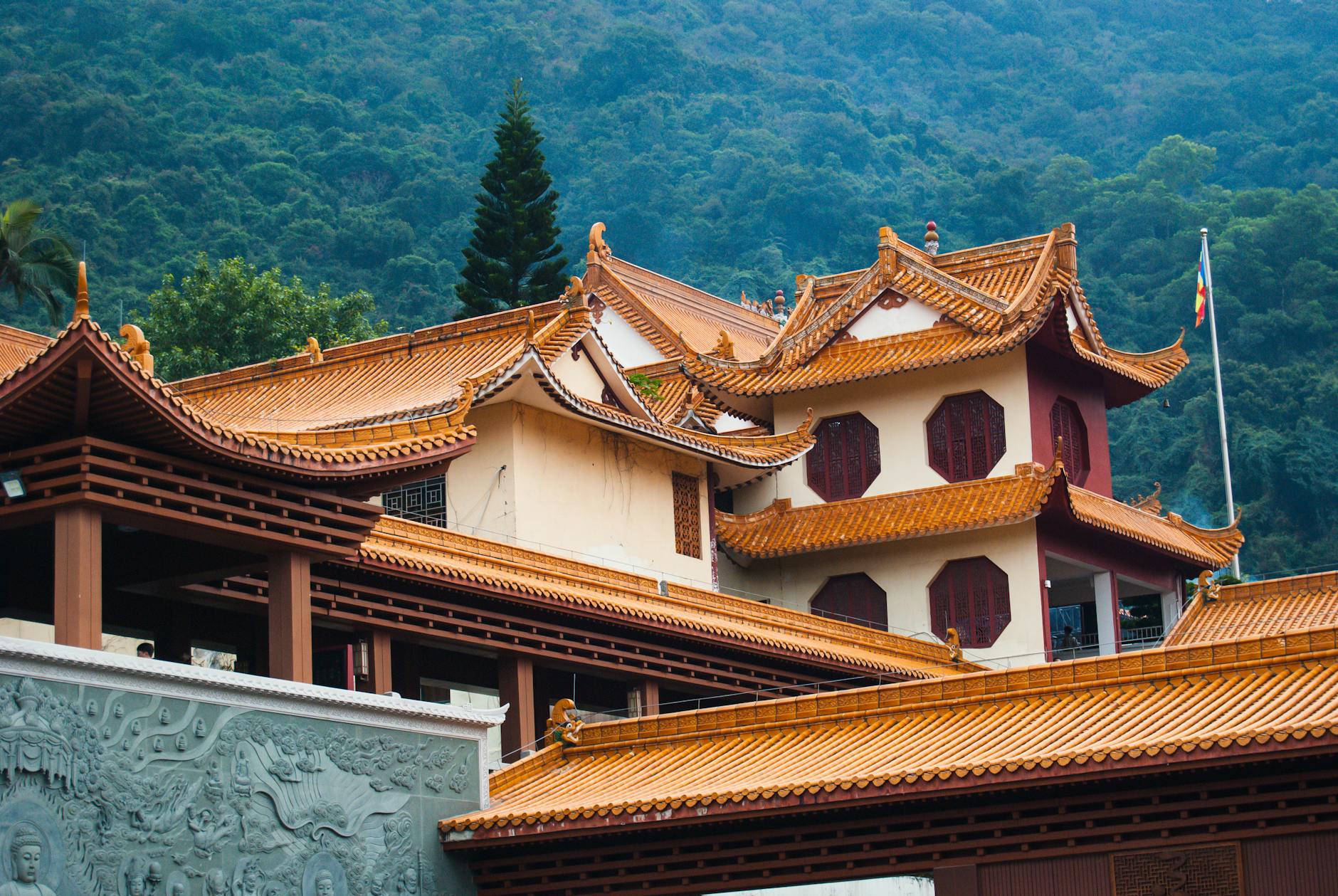 Serene traditional Chinese temple with ornate roofs against lush mountainous backdrop.