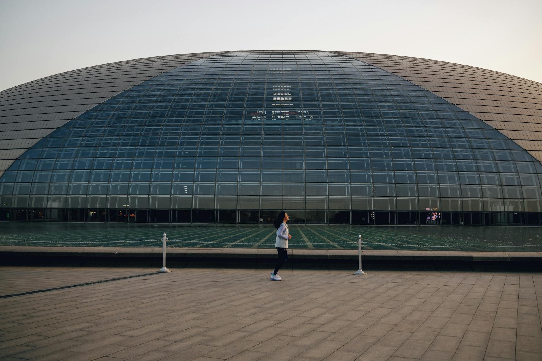 National Centre for Performing Arts with a woman walking in front during the day.