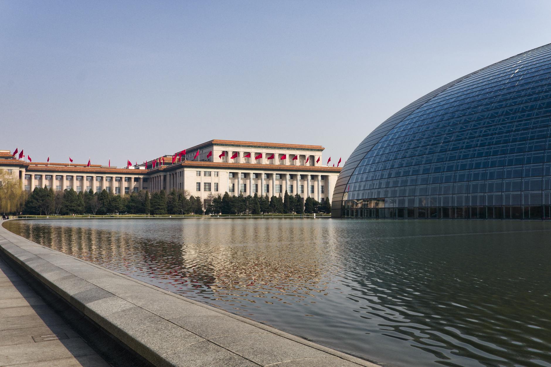 Discover Beijing's modern and traditional architecture reflected in a serene lakeside view.