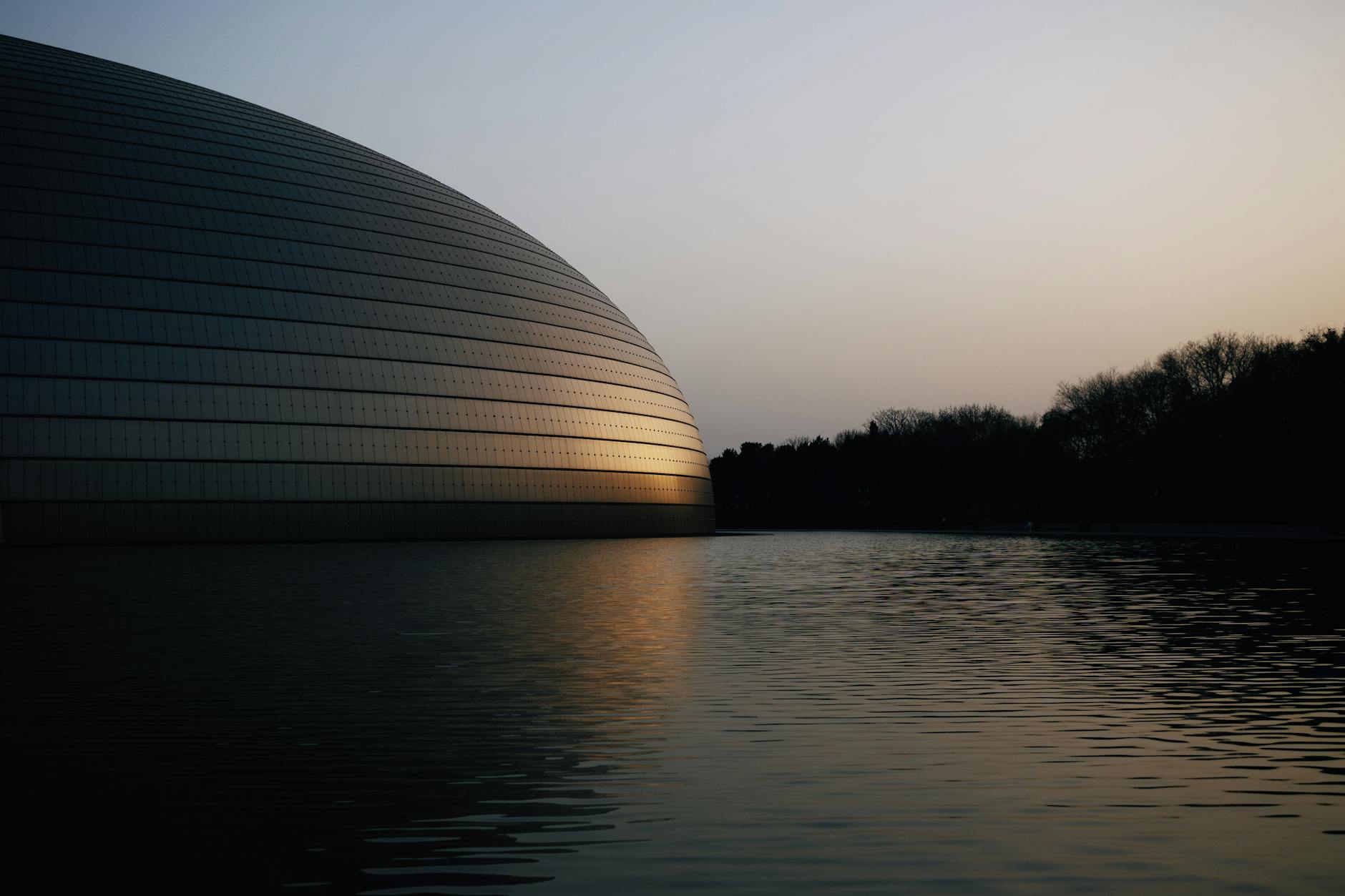 Dramatic sunset reflects off the iconic National Centre for the Performing Arts in Beijing, China.