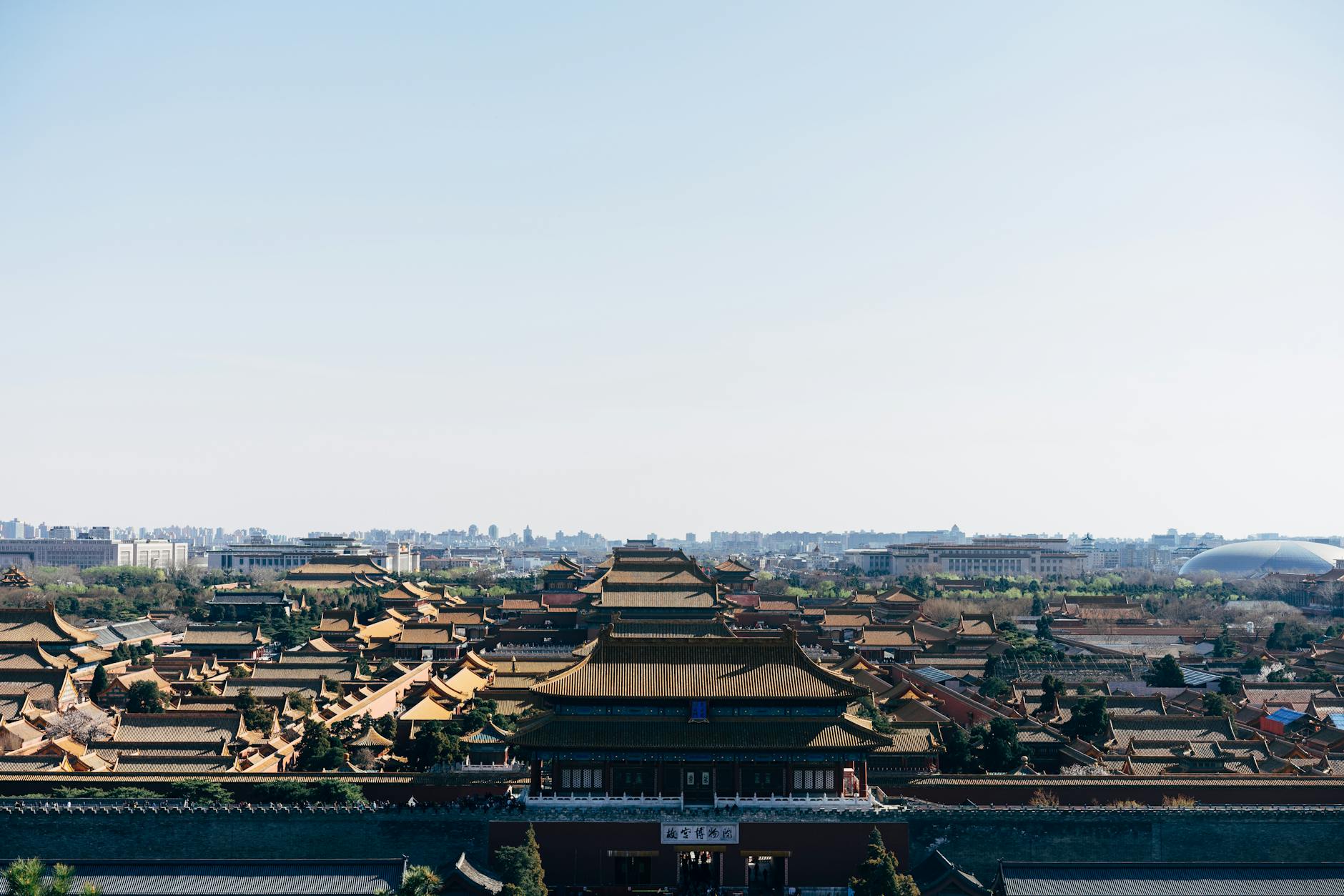 Aerial view of the Forbidden City in Beijing, showcasing historic architecture and city skyline.