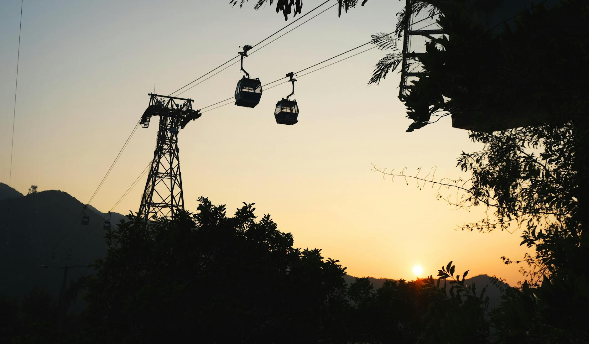 Beautiful silhouette of cable cars during sunset in Hong Kong with a dramatic city landscape.