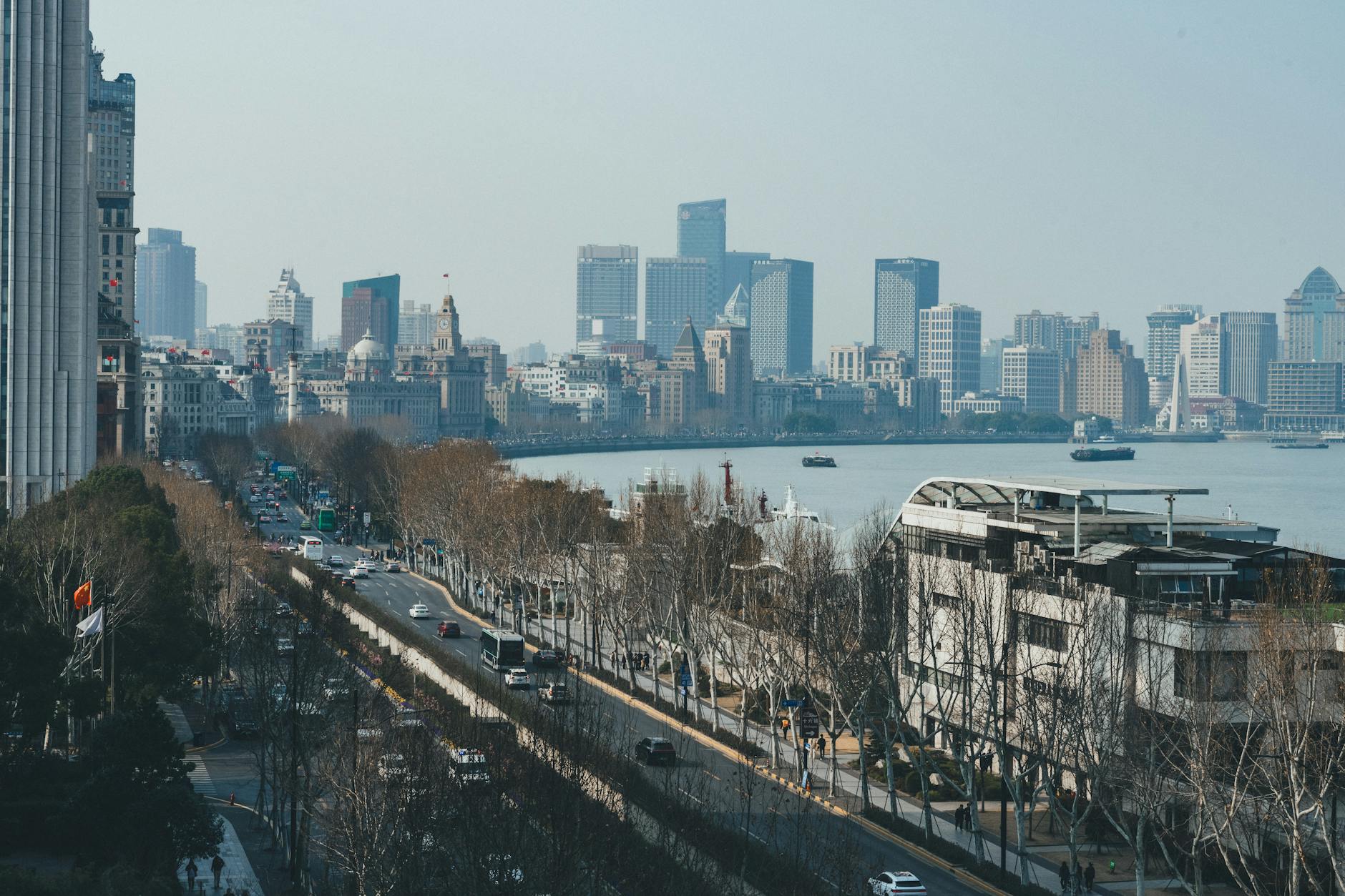 Aerial view of Shanghai's Pudong skyline across the Huangpu River from The Bund, capturing the modernity of the cityscape.