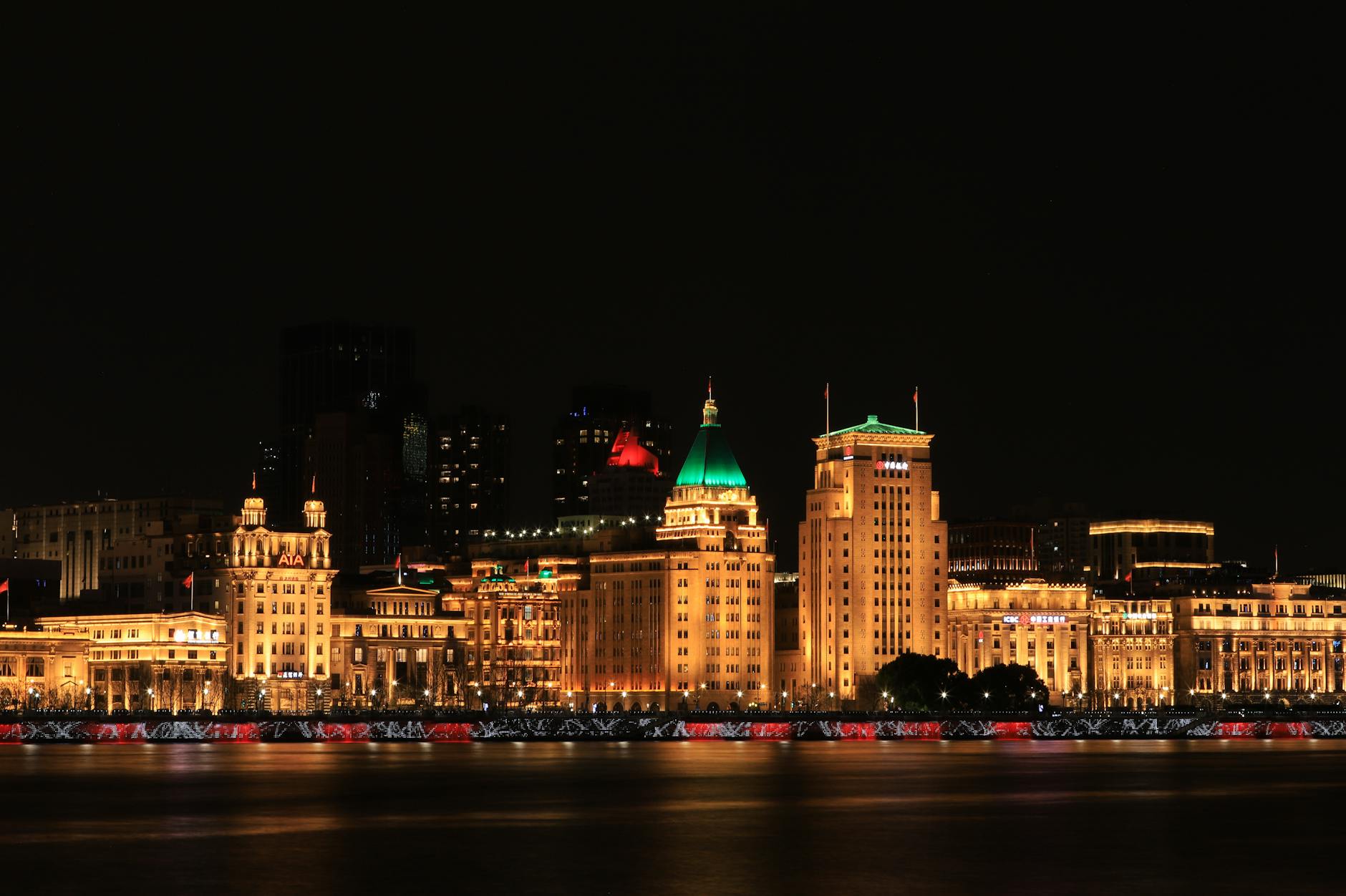 Stunning night view of Shanghai's Bund with illuminated historic buildings along the Huangpu River.