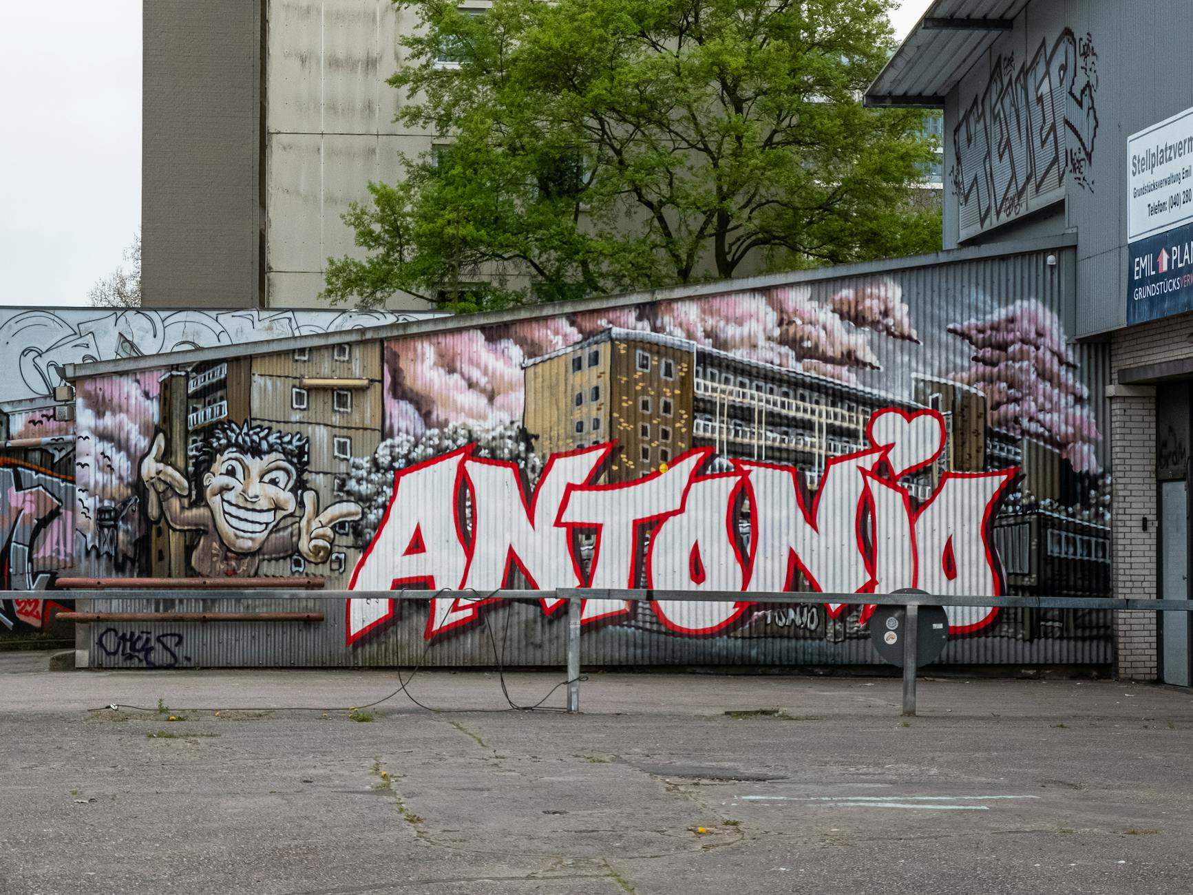 Colorful street art mural with the text 'Antonio' and urban scene.