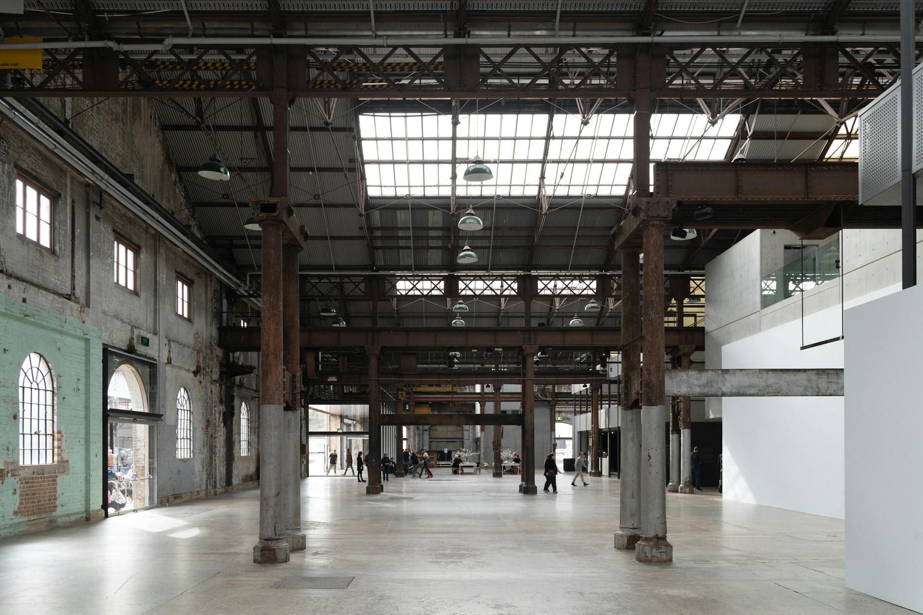 A spacious, light-filled industrial warehouse in Sydney with exposed beams and people walking.