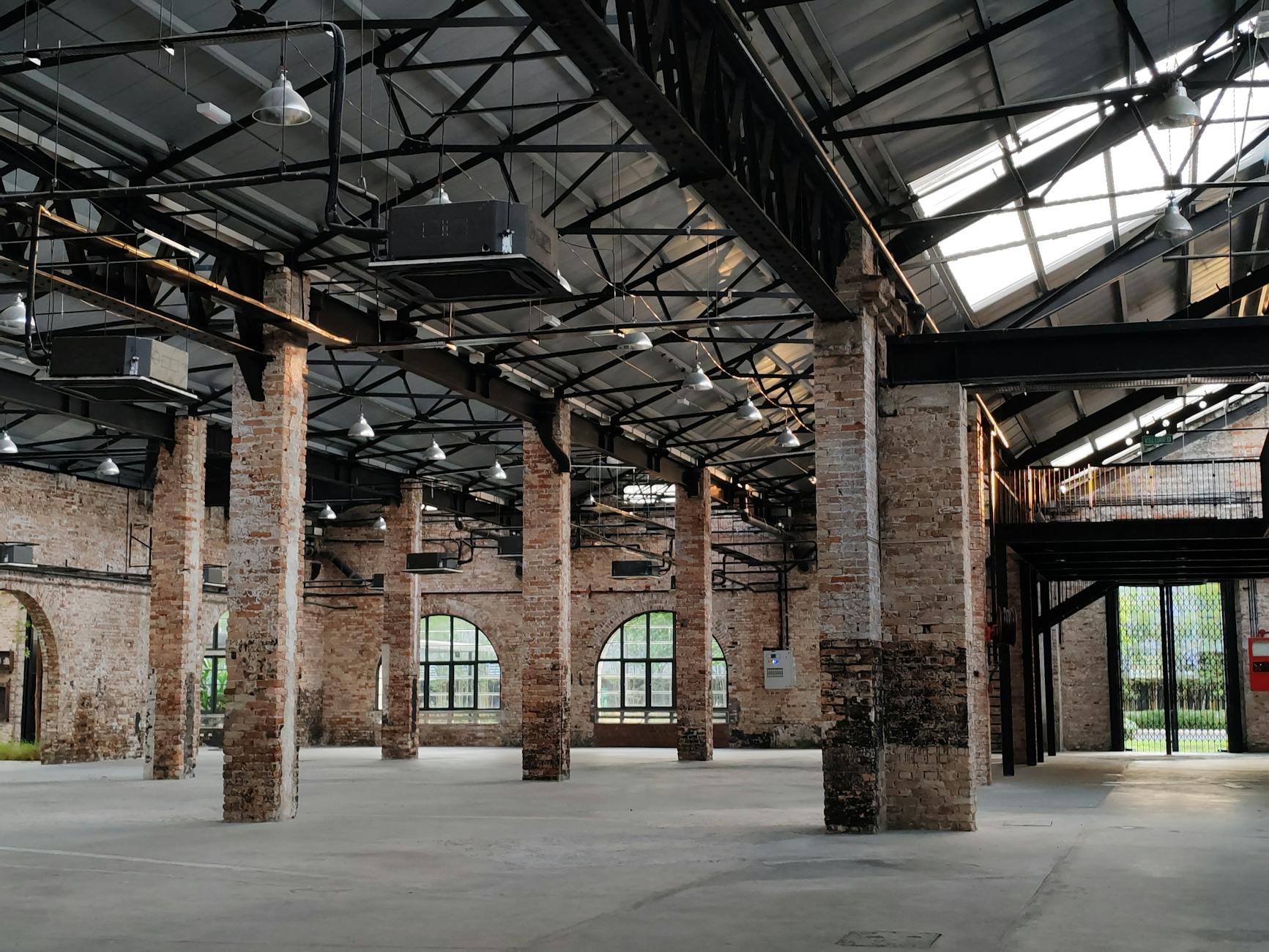Spacious industrial warehouse with exposed brick walls and steel framework, illuminated by natural light.