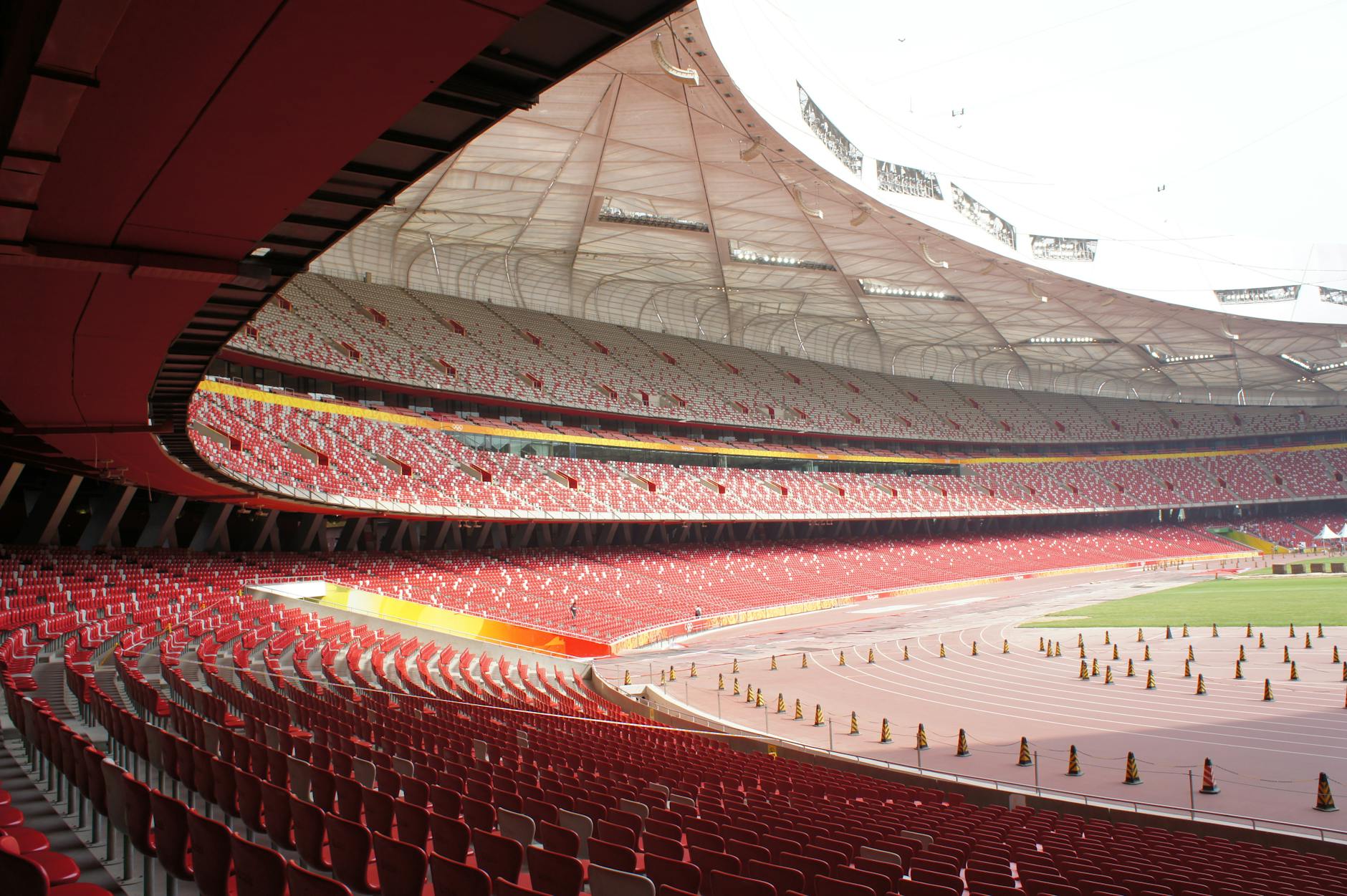 Empty seats and expansive view of Beijing National Stadium, bathed in daylight.
