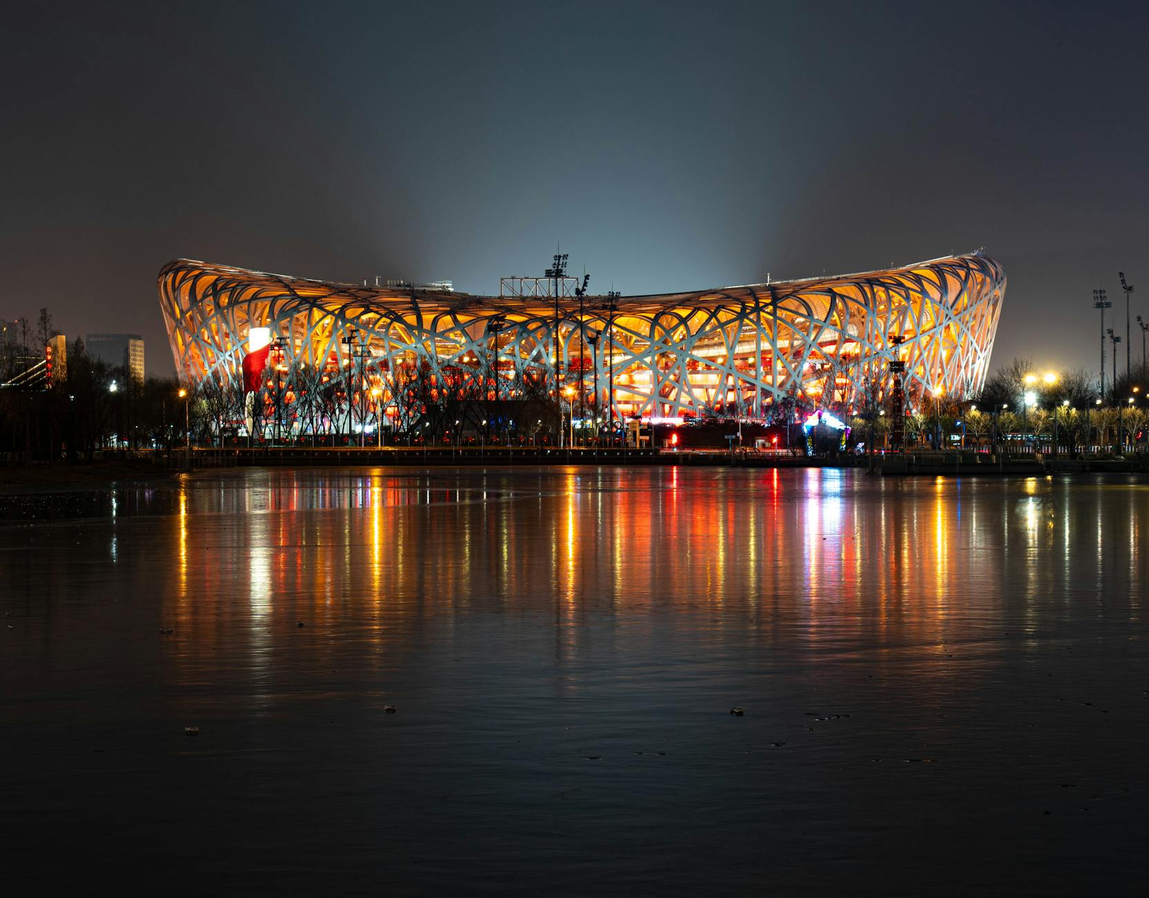 The stunning Bird's Nest stadium reflecting in the water at night in Beijing.