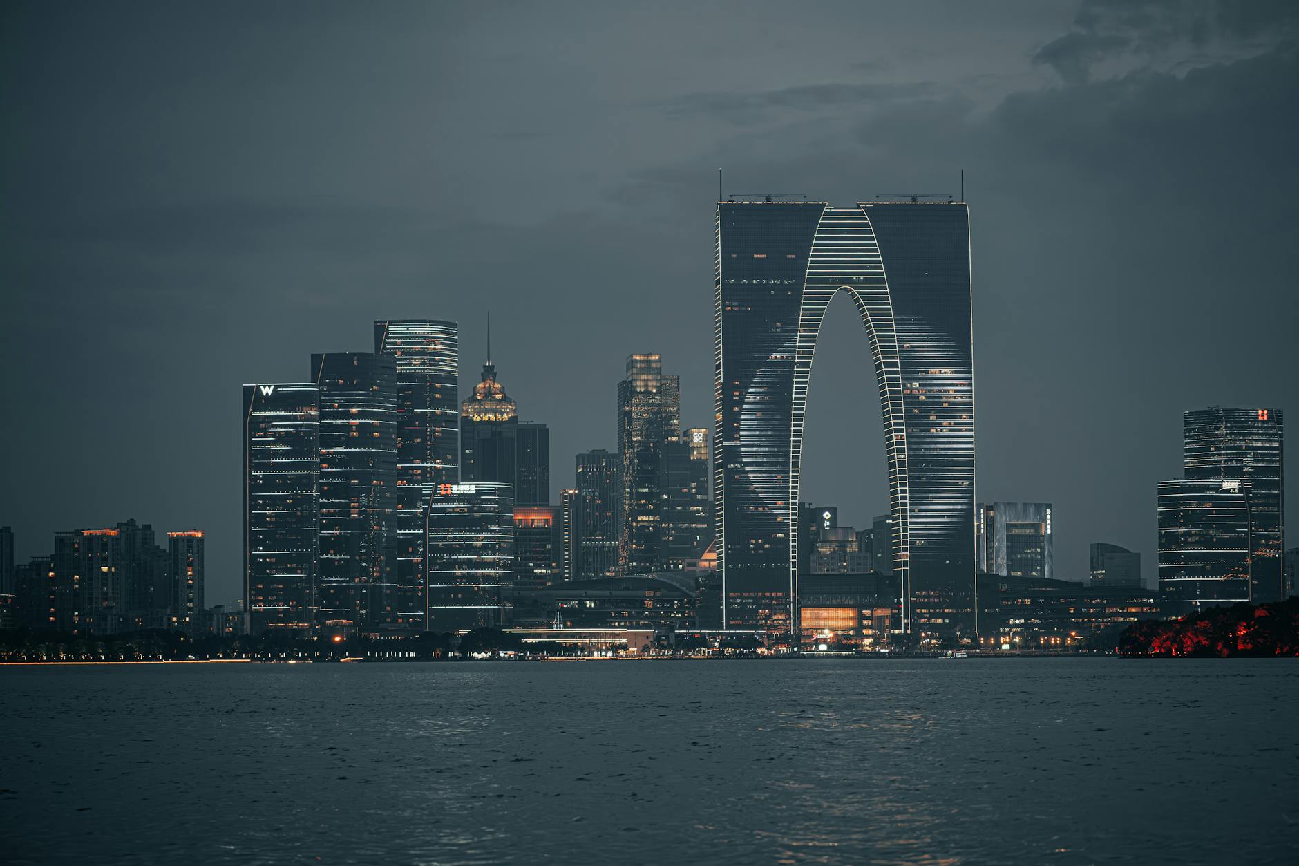 Twilight view of Suzhou skyline featuring the Gate to the East reflected in water.