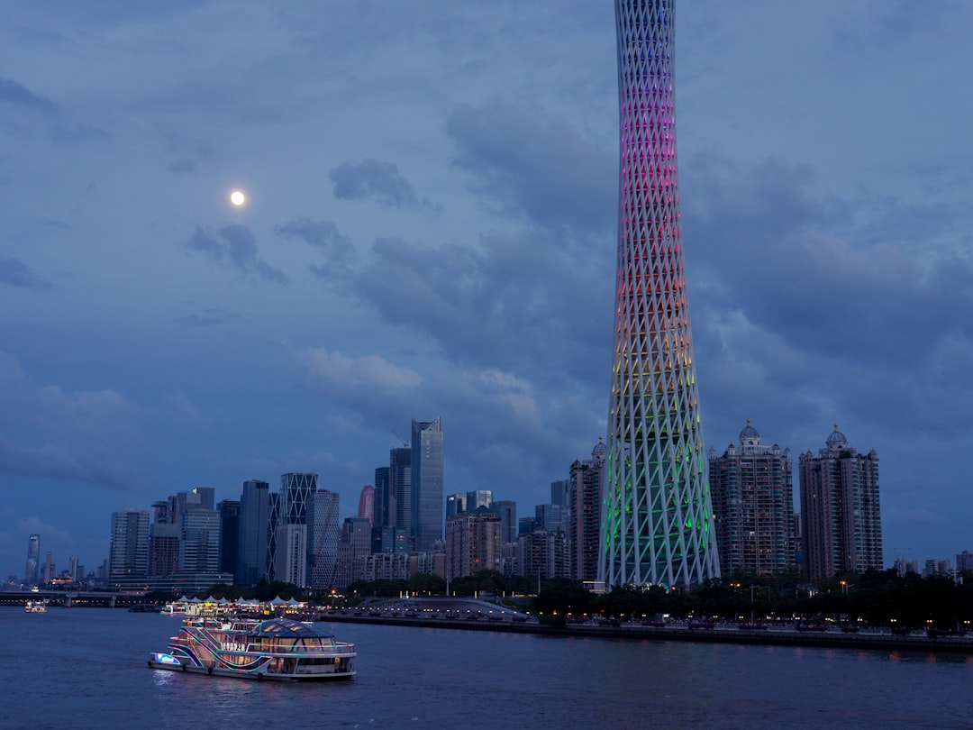 Modern cityscape with illuminated tower and boat at dusk