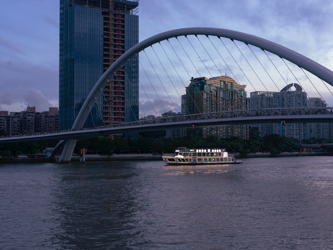 A boat sails under a modern bridge at dusk.