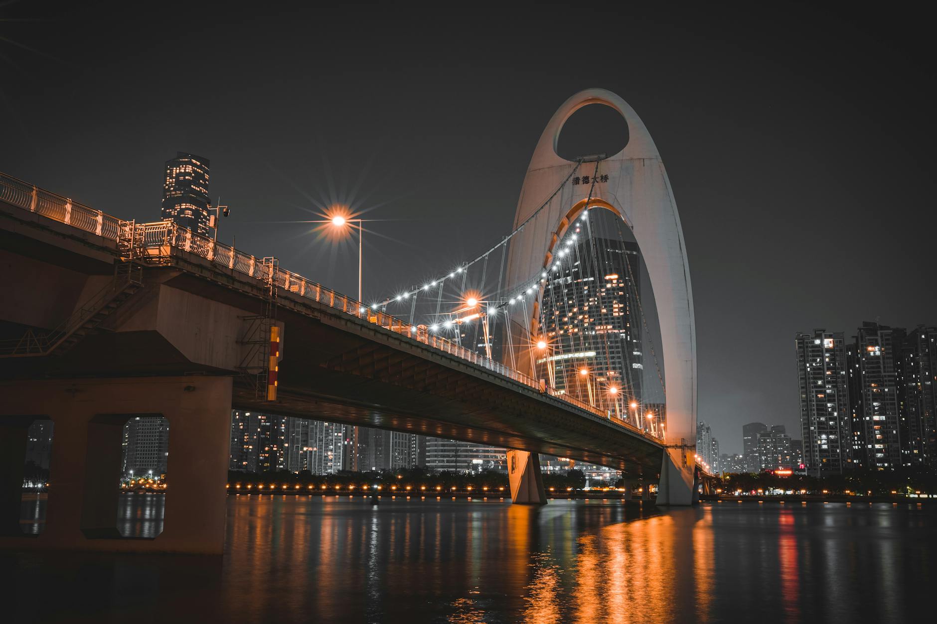 Stunning night view of Liede Bridge over Pearl River in Guangzhou with modern architecture and city lights.