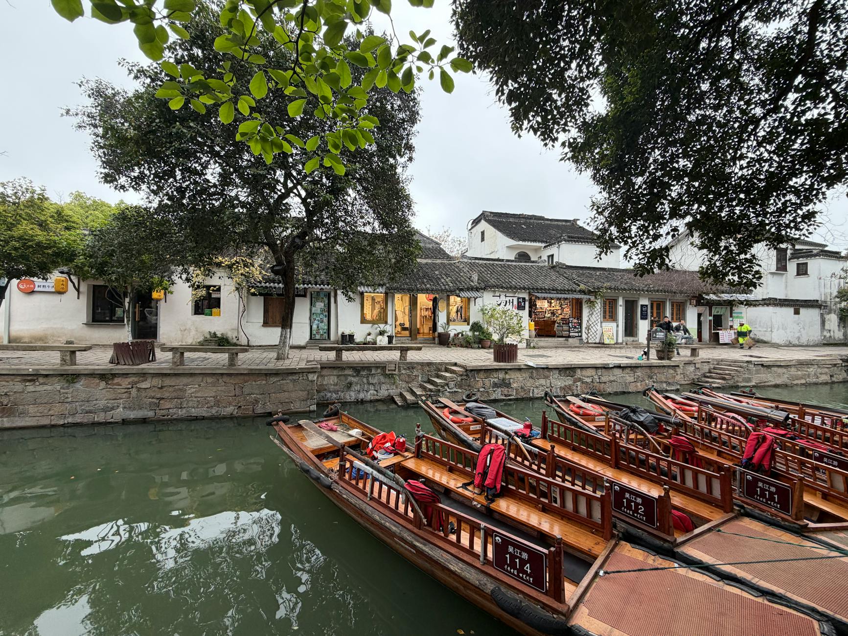Charming scene of a Chinese village by the river with traditional wooden boats docked.