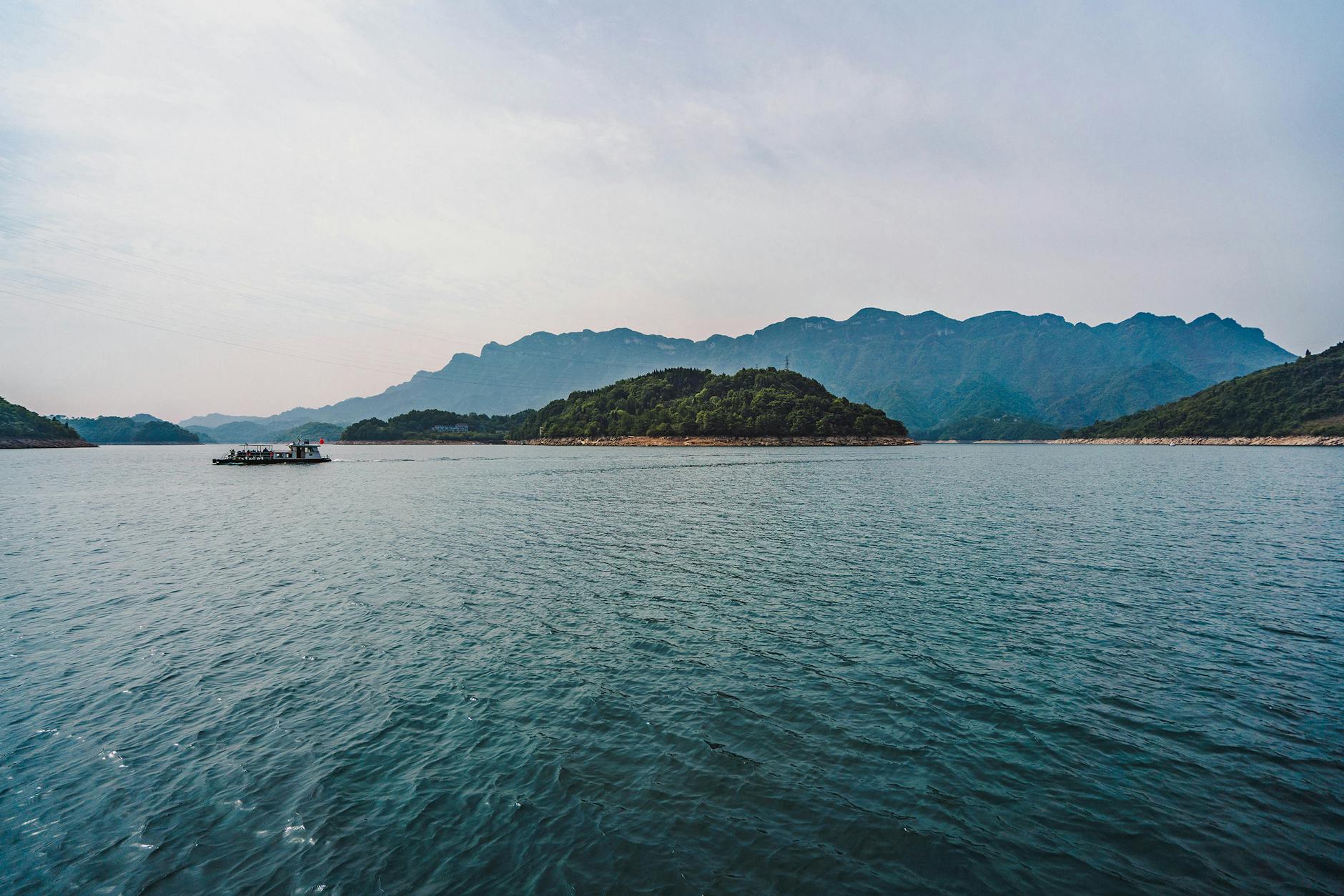 Breathtaking view of a tranquil lake with mountain backdrop in Hubei, China, ideal for travel enthusiasts.
