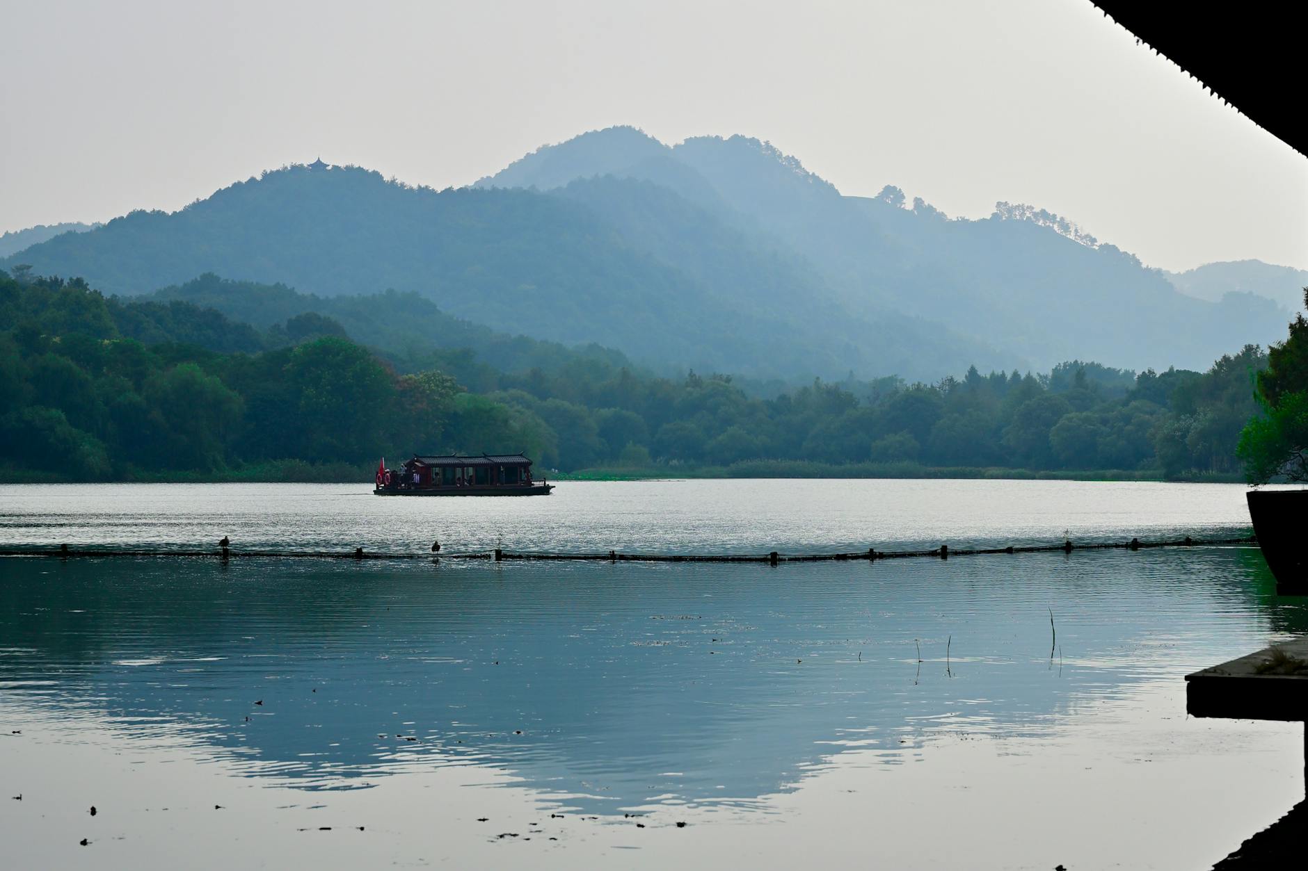 A tranquil scene featuring a boat on a serene lake surrounded by lush greenery and mountains.