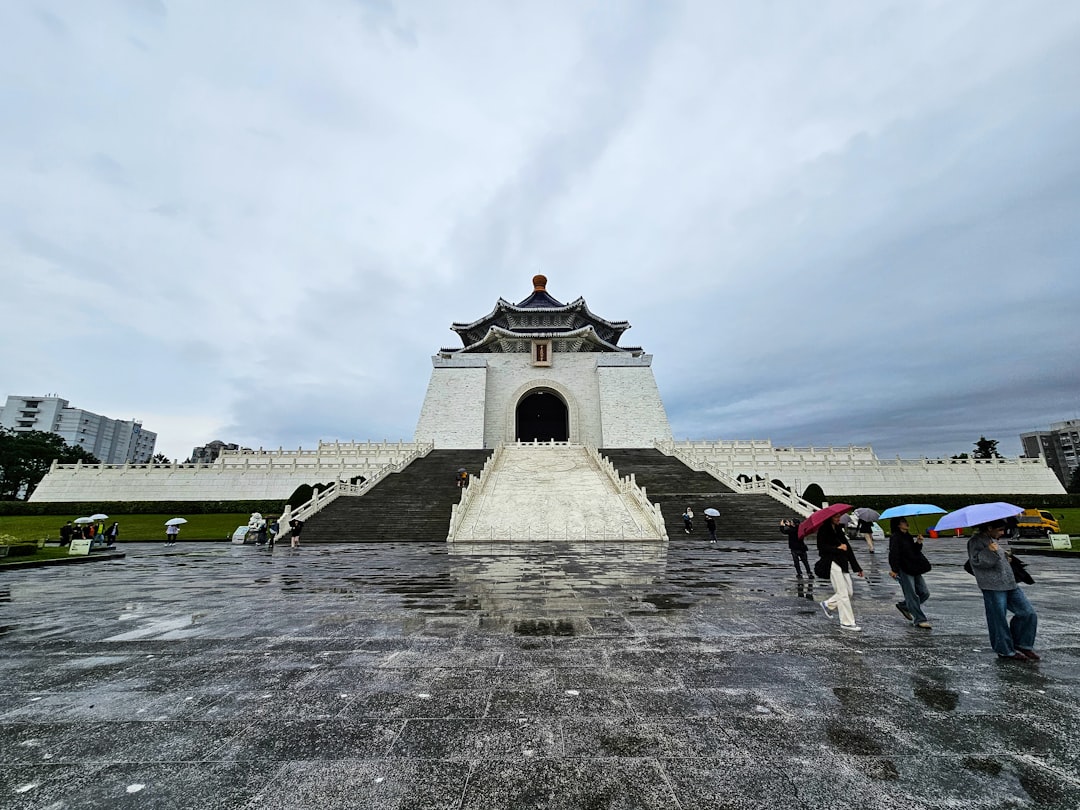 a group of people with umbrellas standing in front of a monument