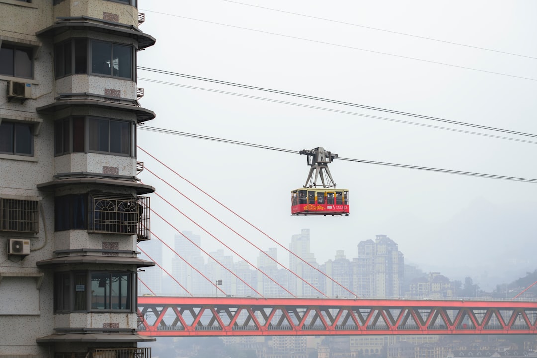 a cable car going over a bridge with a city in the background