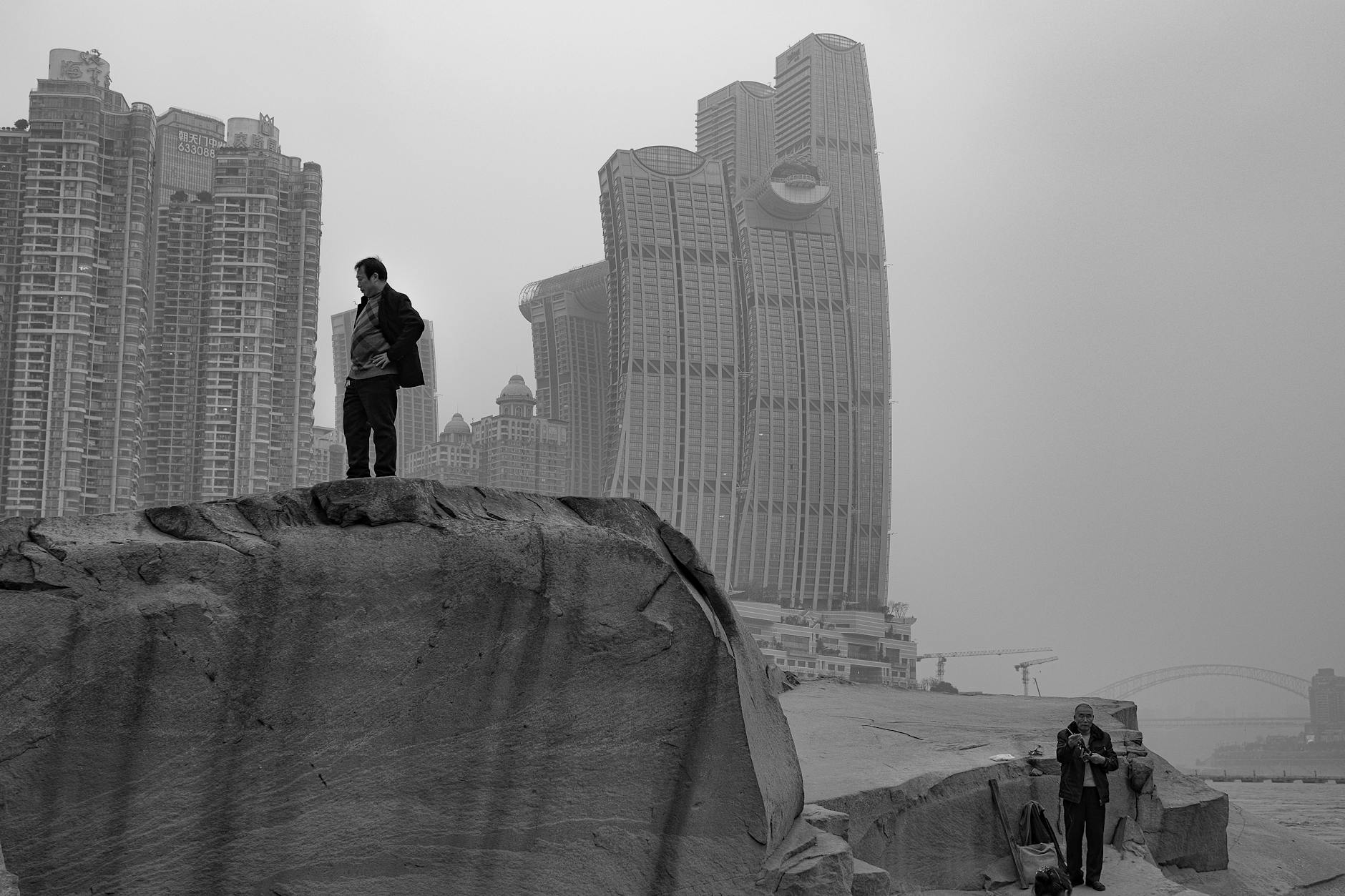 Black and white photo of modern architecture and stone formations in an urban setting.