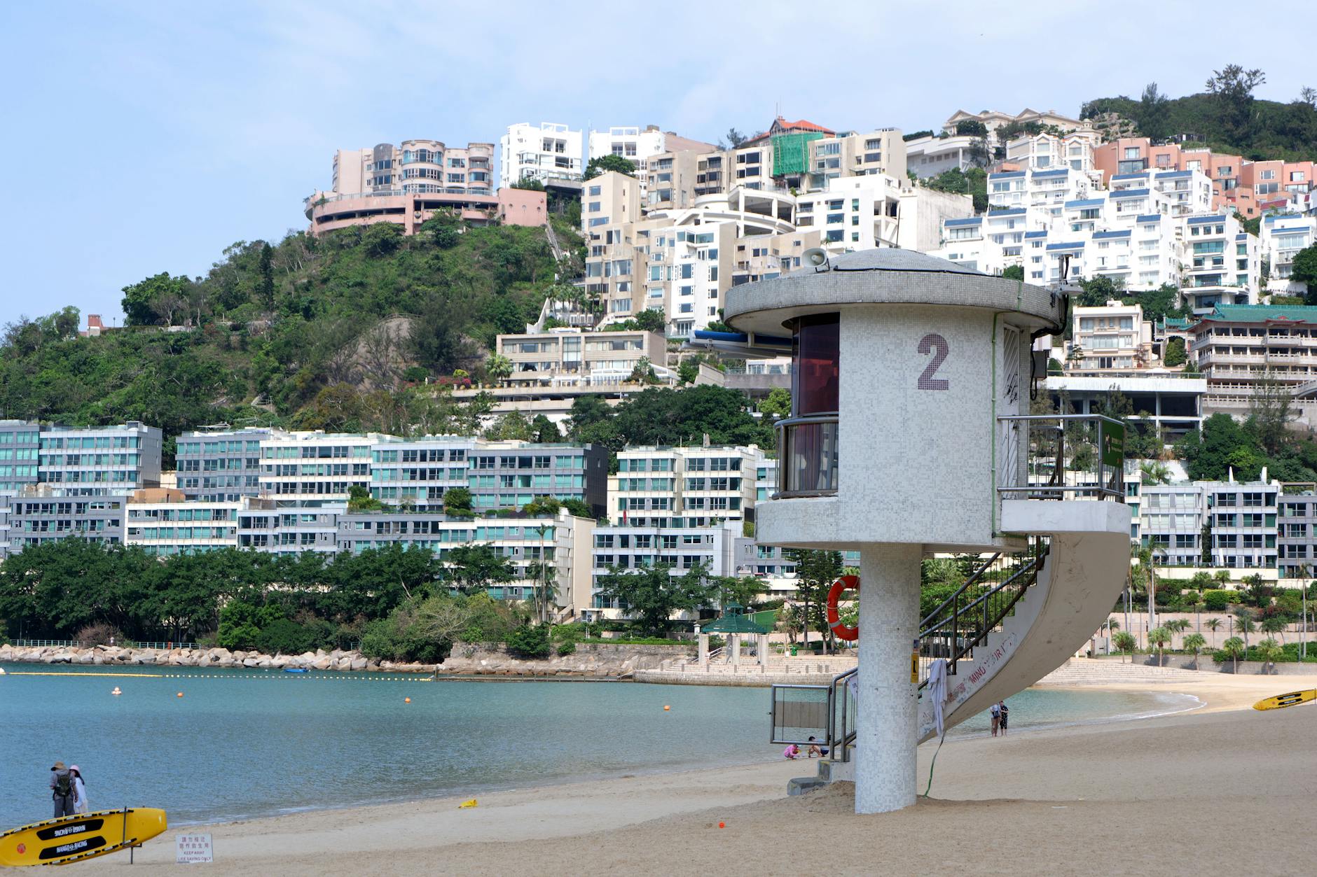 Modern beachfront lifeguard tower overlooking ocean and hillside apartments, ideal for urban travel imagery.