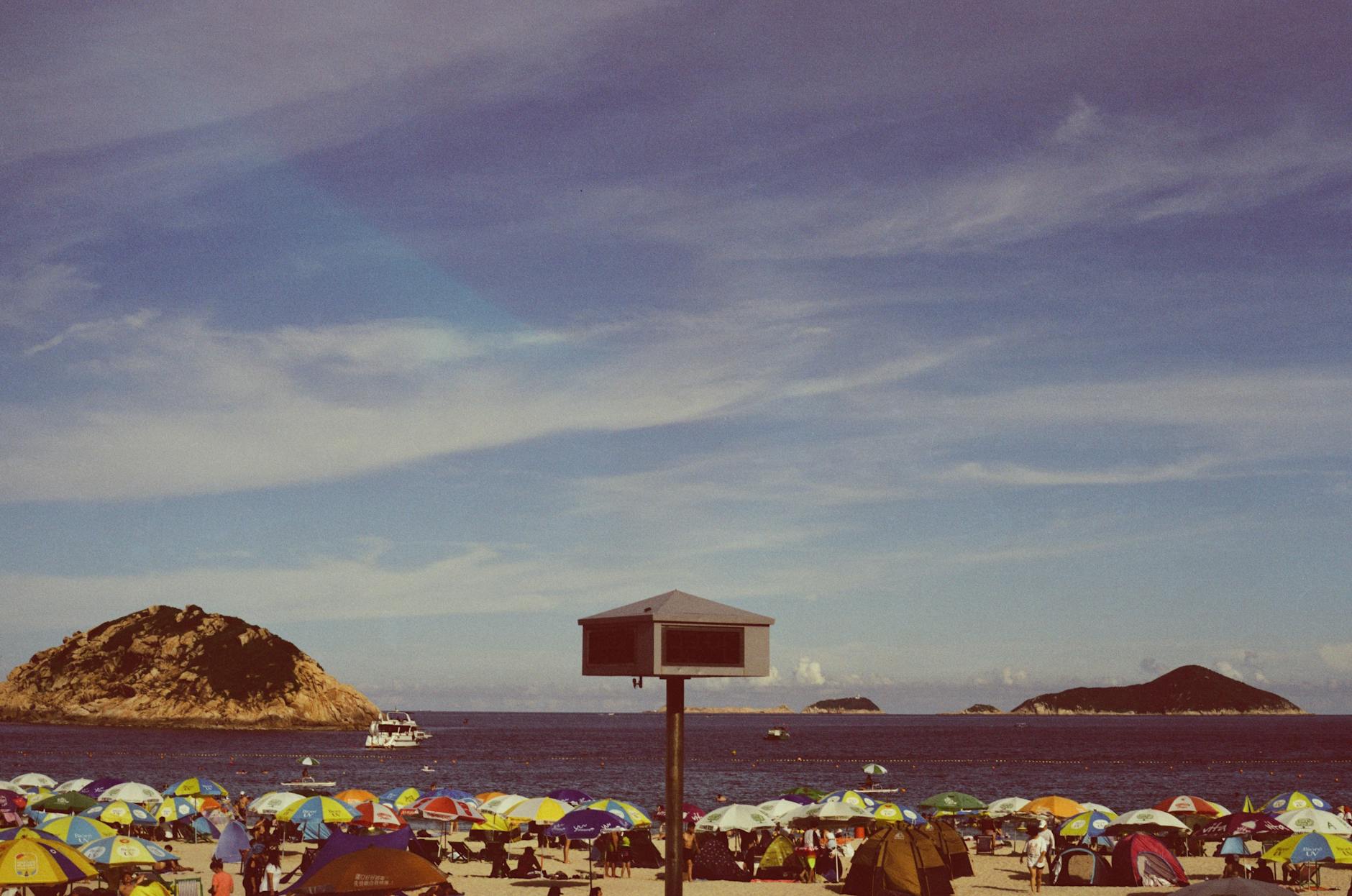 Colorful umbrellas line Repulse Bay Beach under clear skies in Hong Kong, offering a serene summer escape.