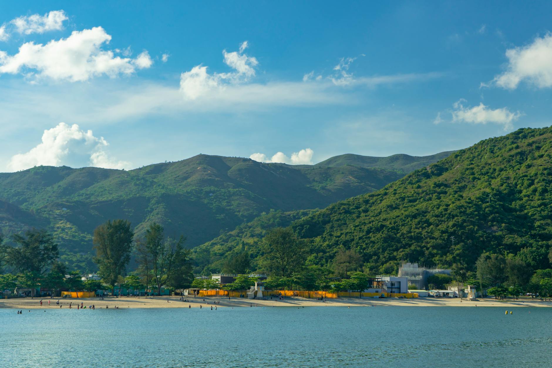 Scenic view of Kowloon beach with lush green hills under a clear blue sky.