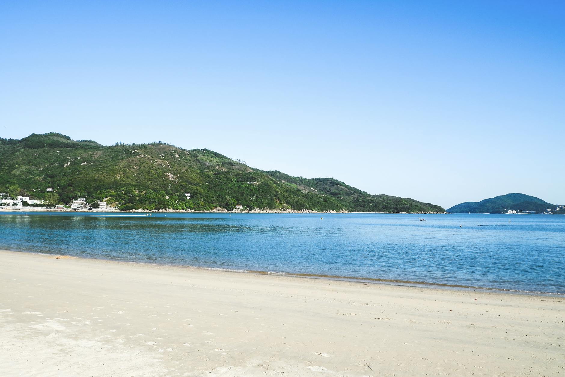 Tranquil beach scene on Lamma Island, Hong Kong with clear blue skies and lush greenery.