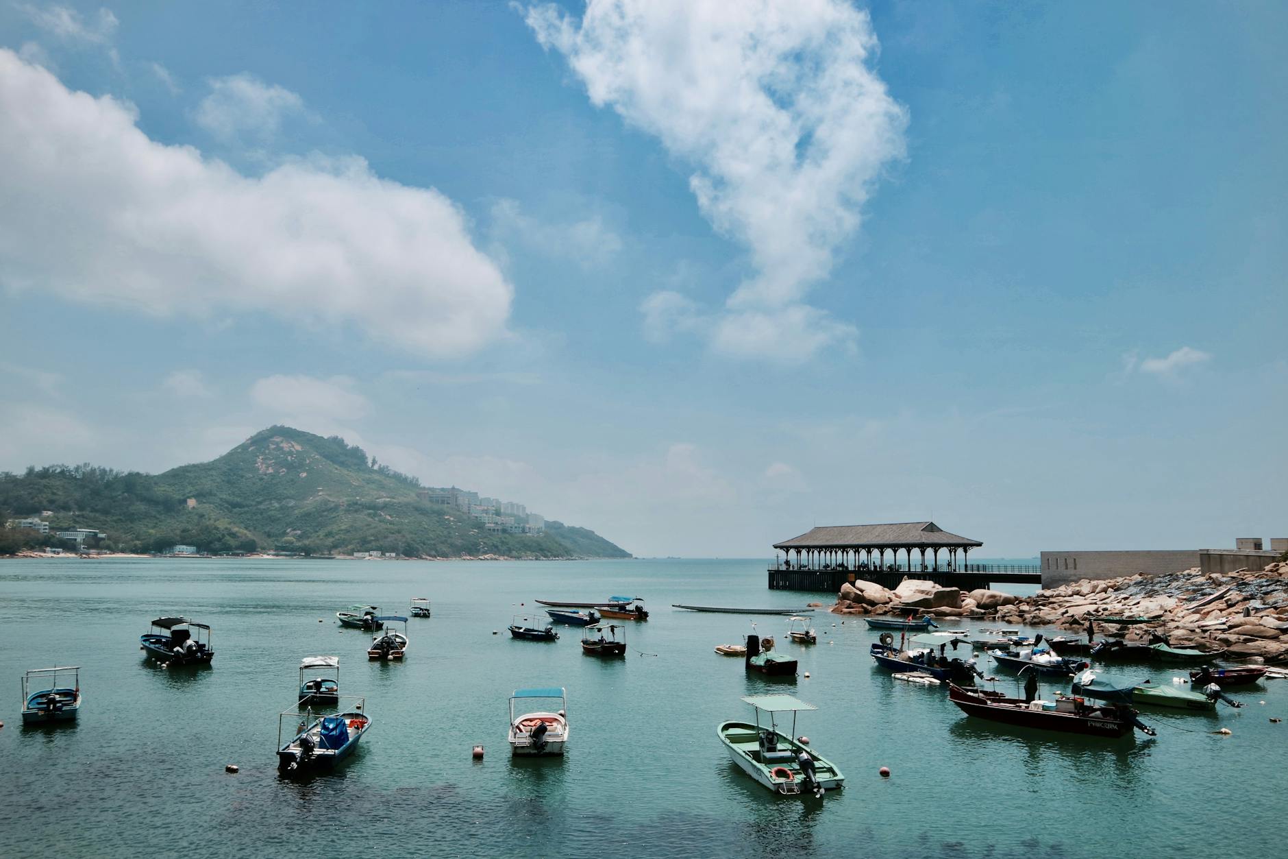 Explore the serene Hong Kong harbor with boats docked under a clear blue sky.