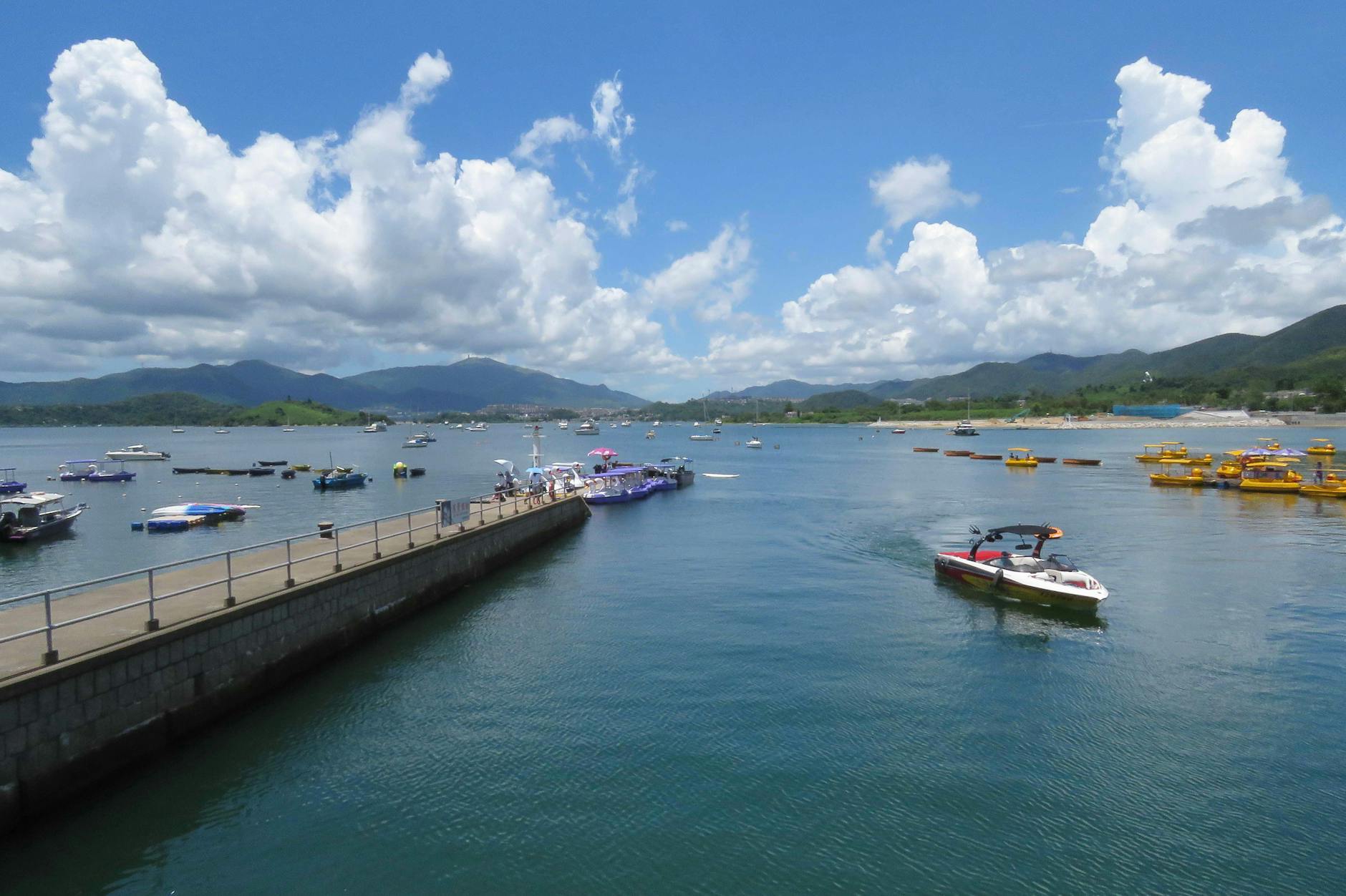 A vibrant coastal view in New Territories, Hong Kong with boats and scenic mountains.